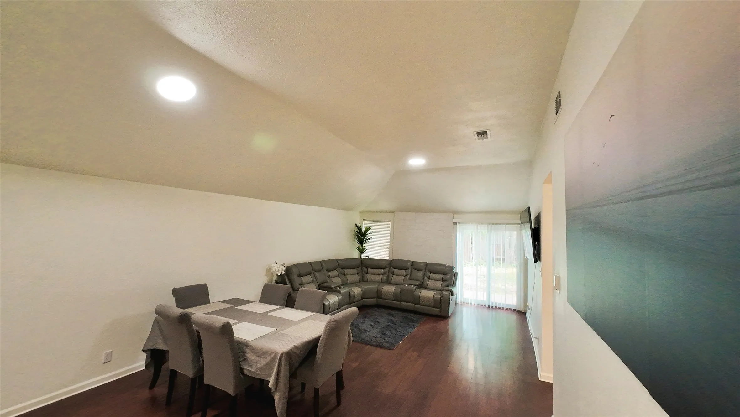 Vaulted ceilings, recessed lighting, wood-finish flooring, white walls, and a sliding glass door