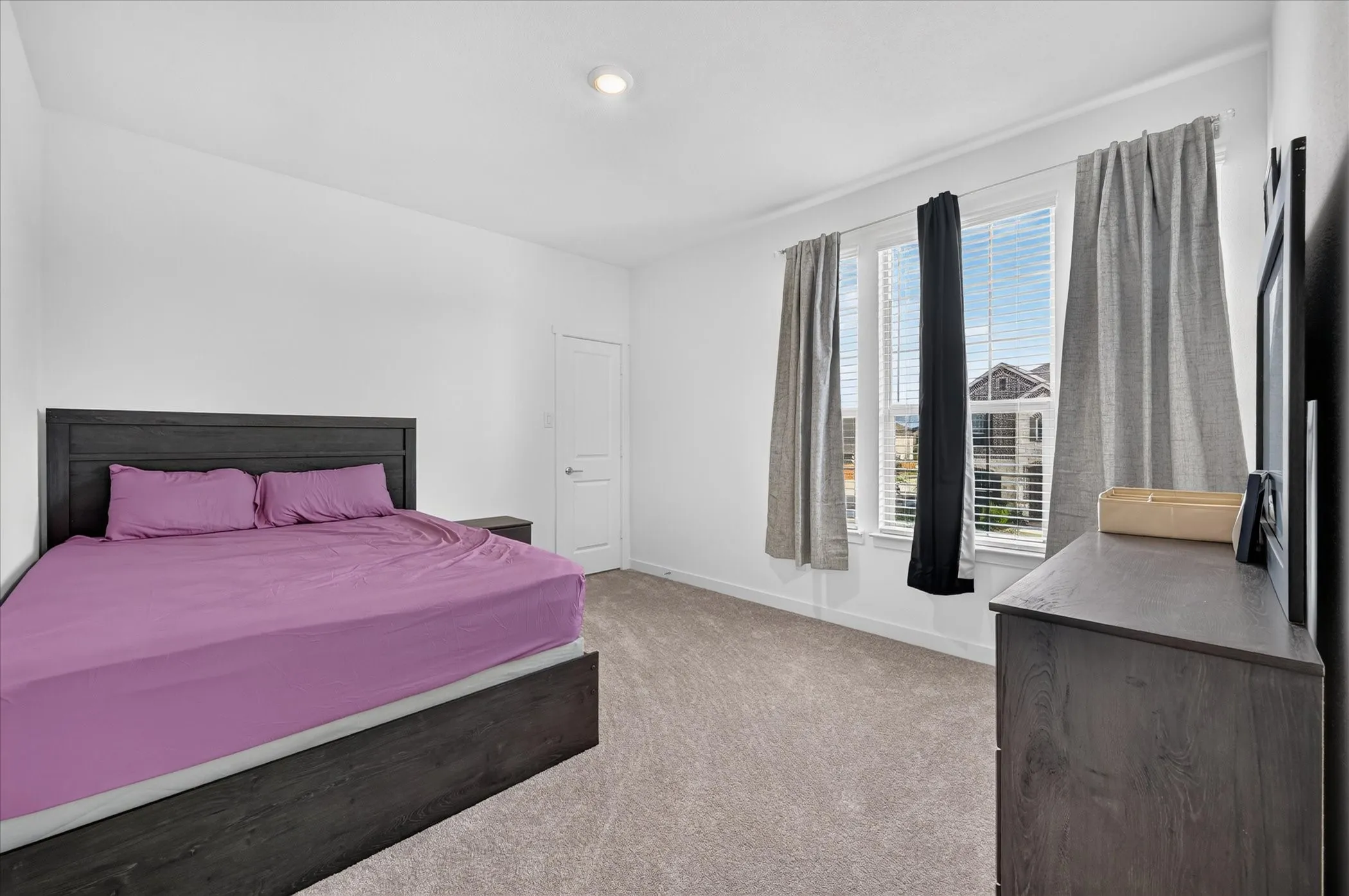 Recessed ceiling lighting, textured carpet flooring, white painted walls, white interior door, and a triple window