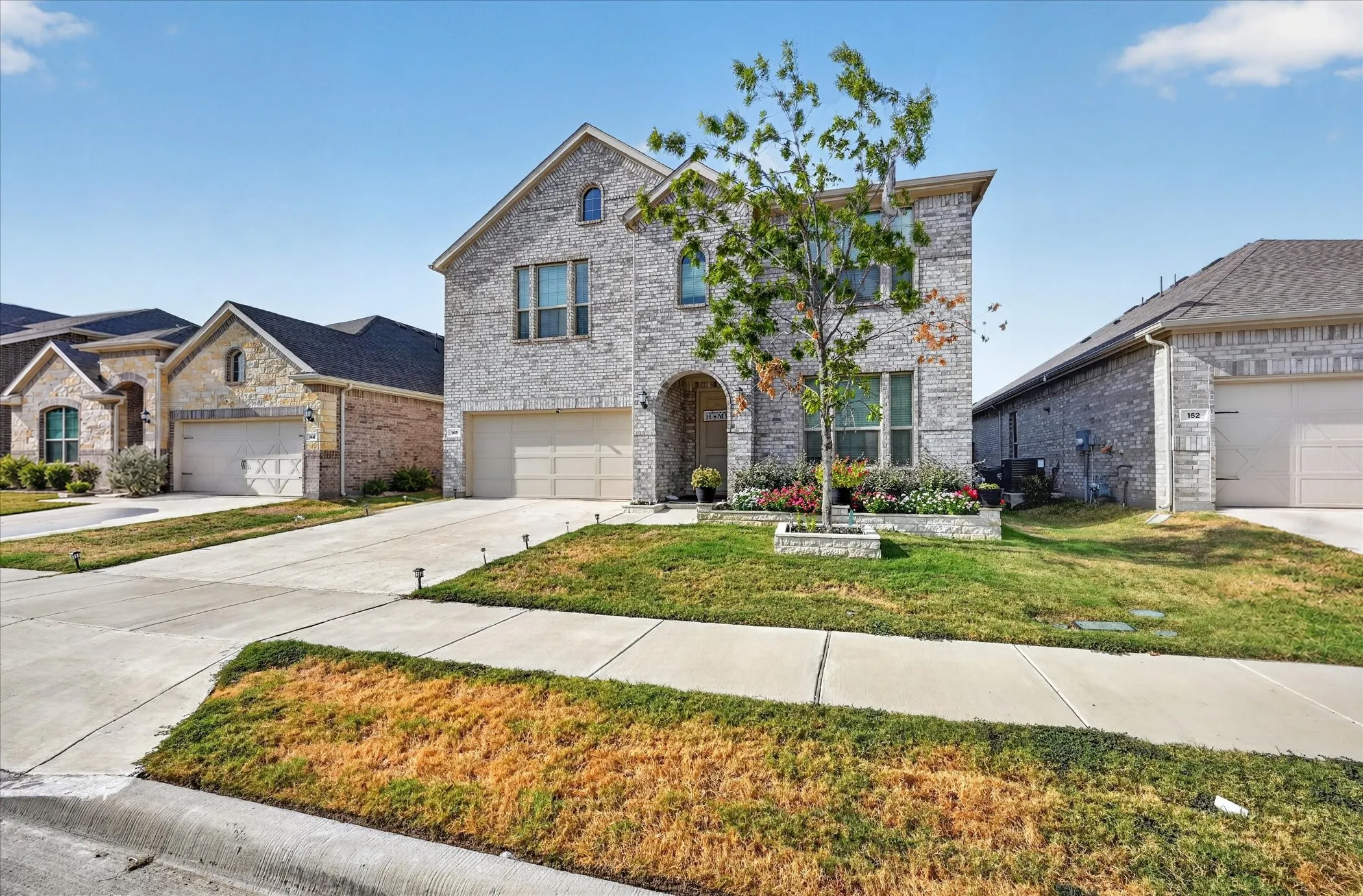 Two-story brick exterior with an arched entryway, attached two-car garage, and established front landscaping