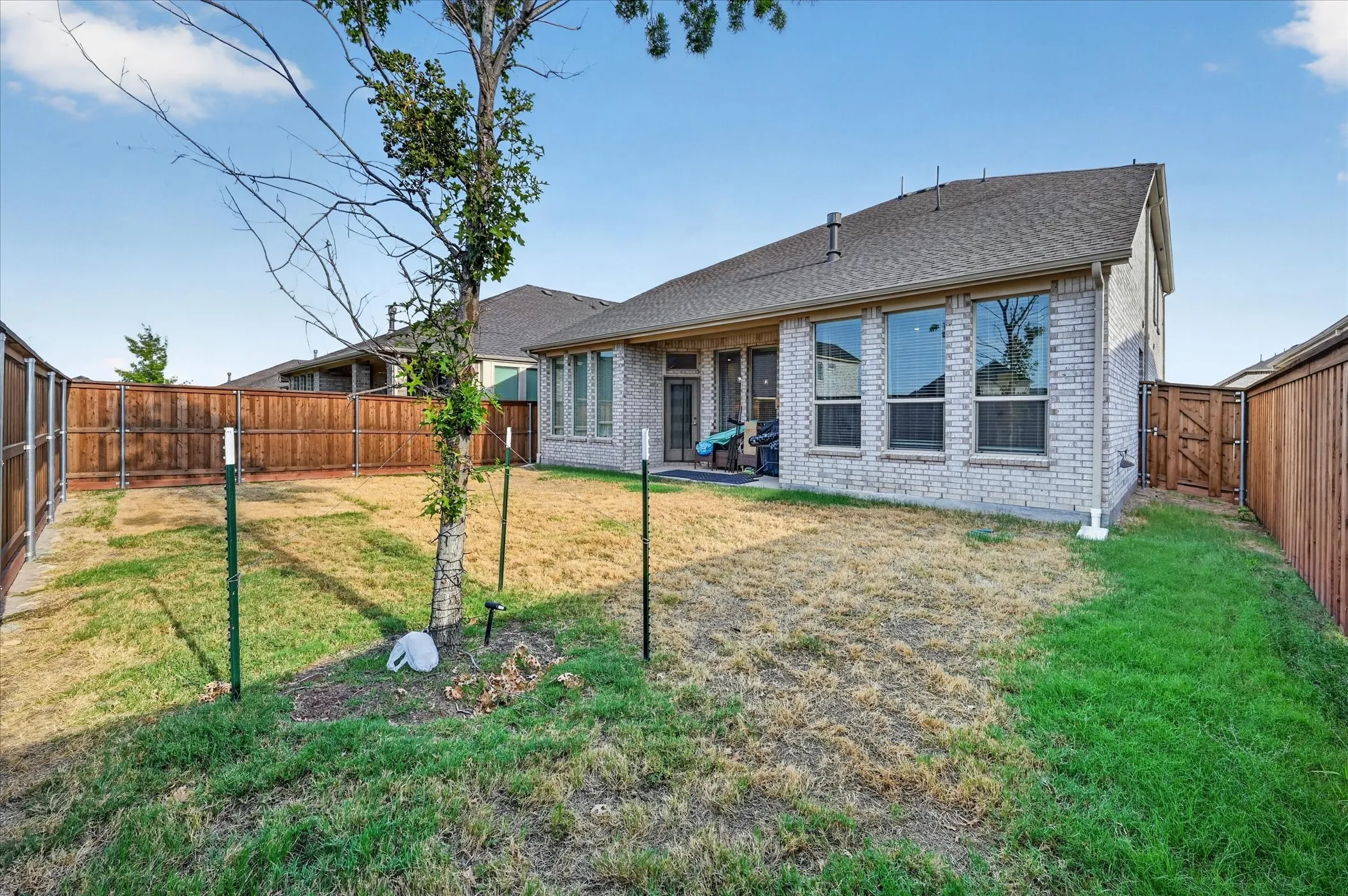 Fenced backyard featuring a brick exterior and a privacy fence
