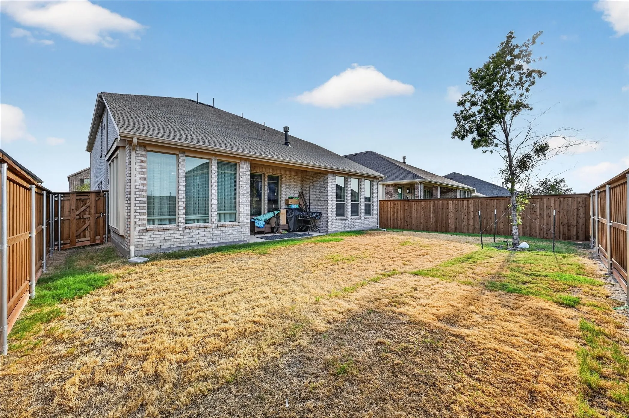 Brick exterior with multiple windows, fenced yard, and a rear patio