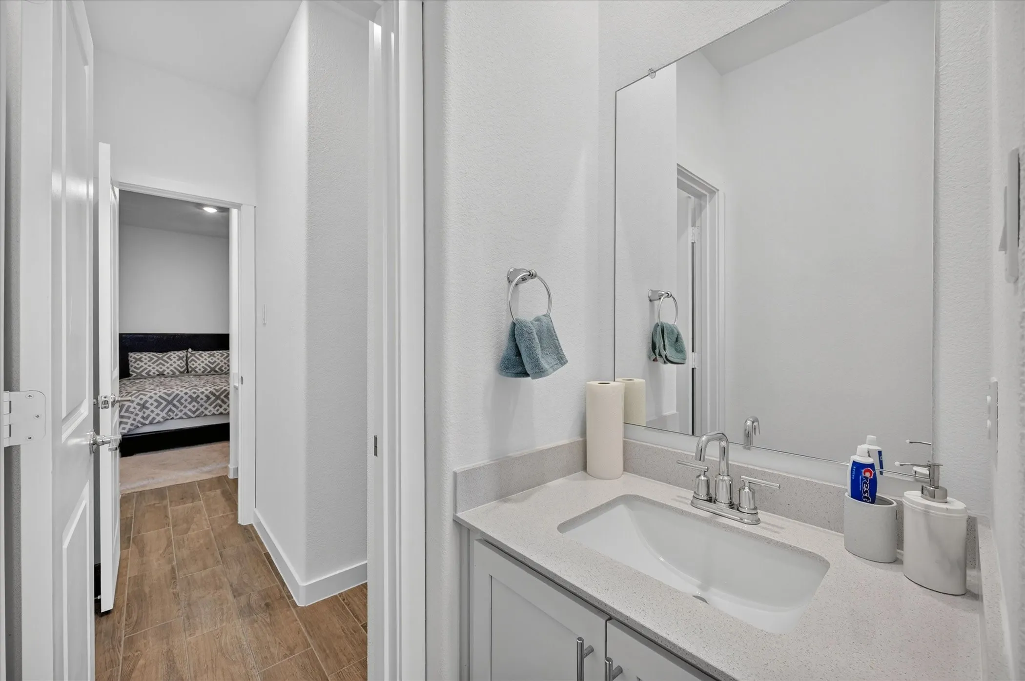 Vanity with integrated sink and quartz countertop, chrome faucet, and large wall mirror