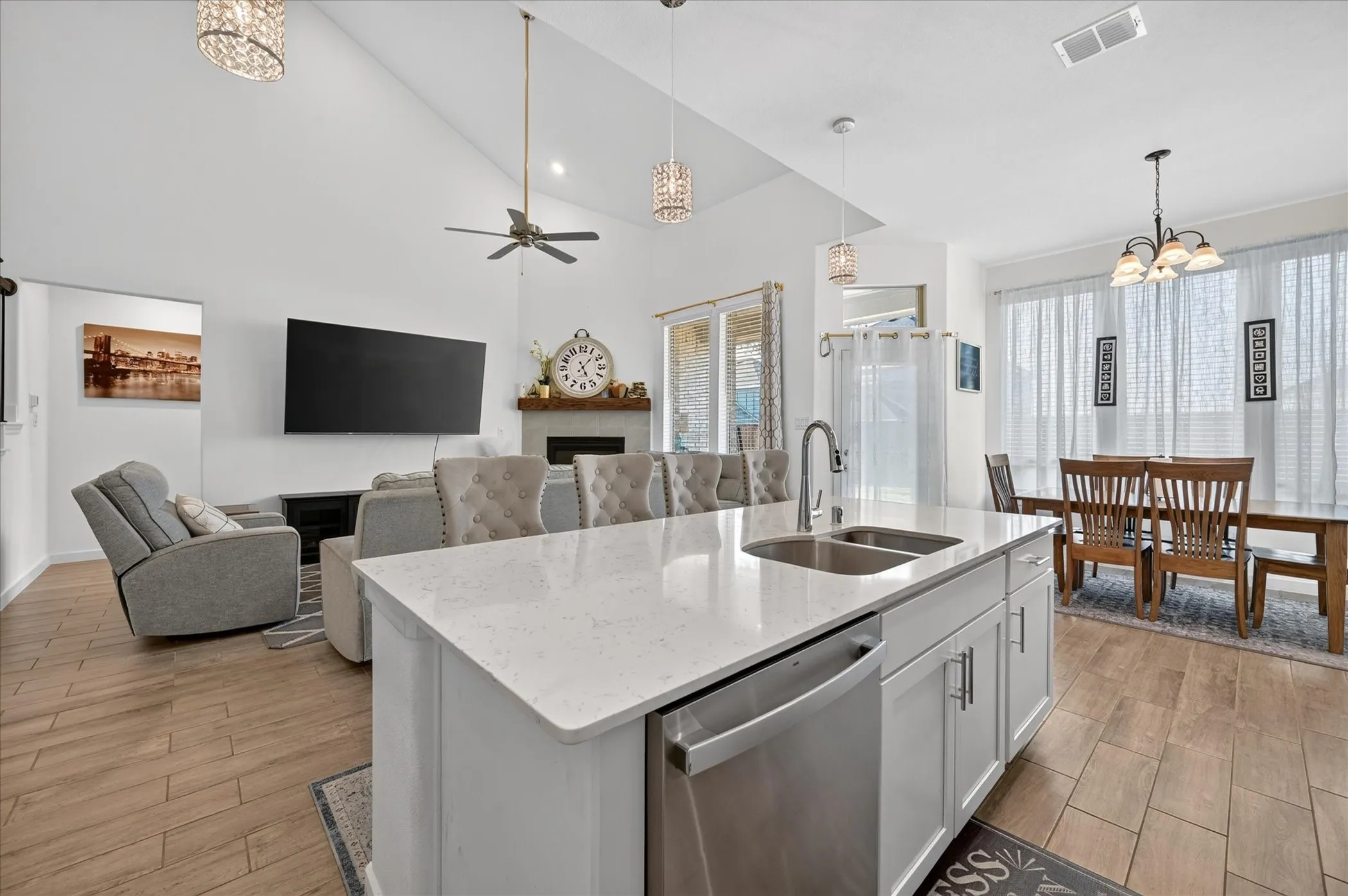 Kitchen island with a double basin sink, stainless steel dishwasher, and white cabinetry