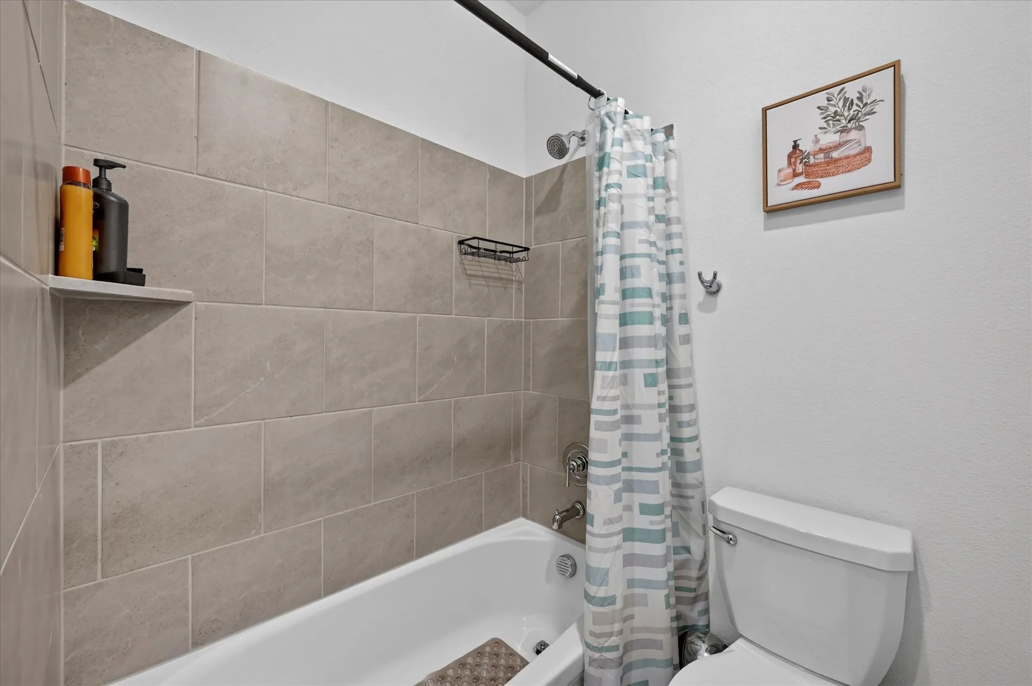 Bathtub with tile surround, built-in shelving, and polished chrome fixtures