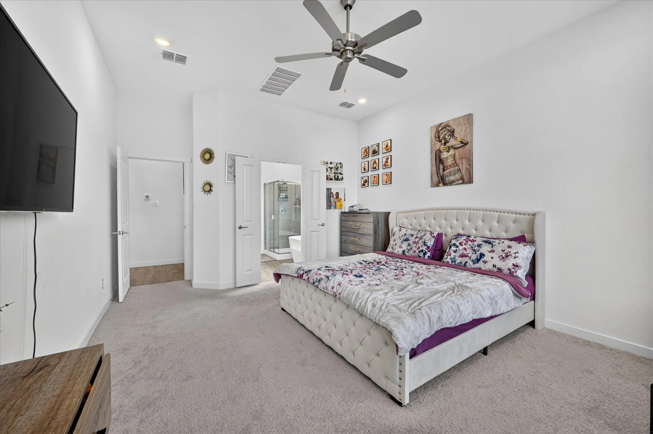 Carpeted flooring, vaulted ceiling, ceiling fan, recessed lighting, and a bathroom entrance featuring a glass-enclosed shower