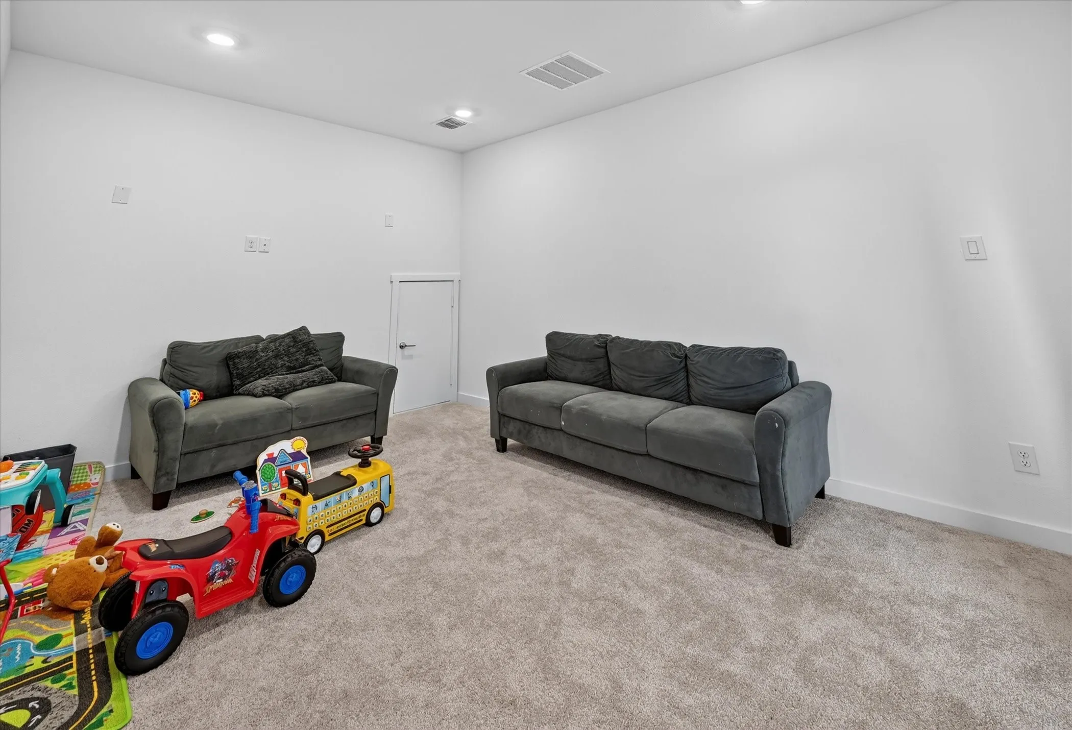 Recessed lighting, light-colored carpeting, white wall finishes, and a white door