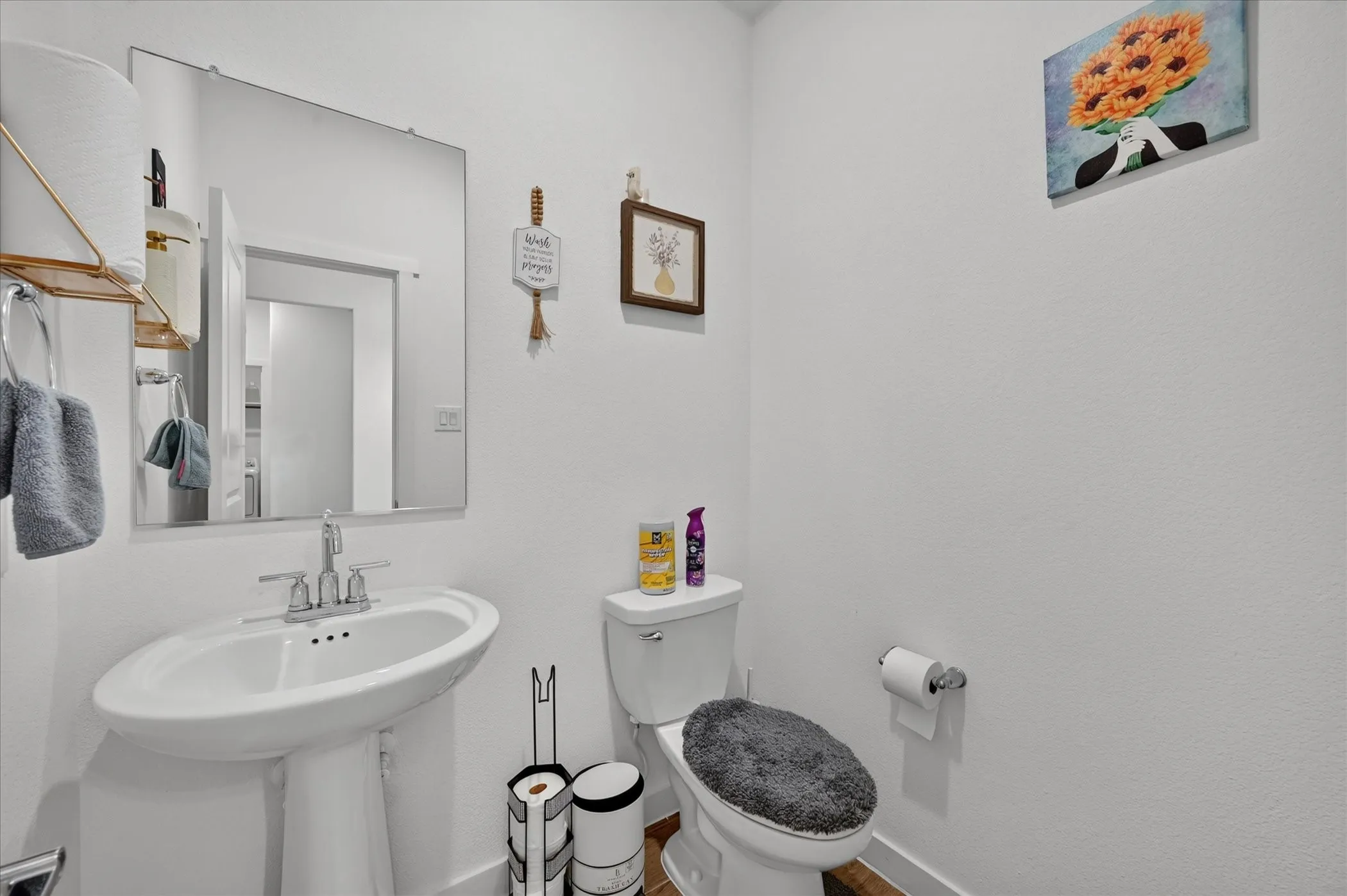 Pedestal sink with chrome faucet, toilet, wall-mounted mirror, and white walls