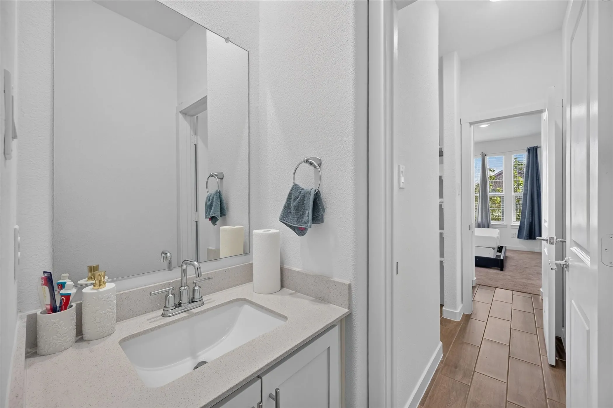 Vanity with integrated sink, polished chrome faucet, and expansive wall mirror