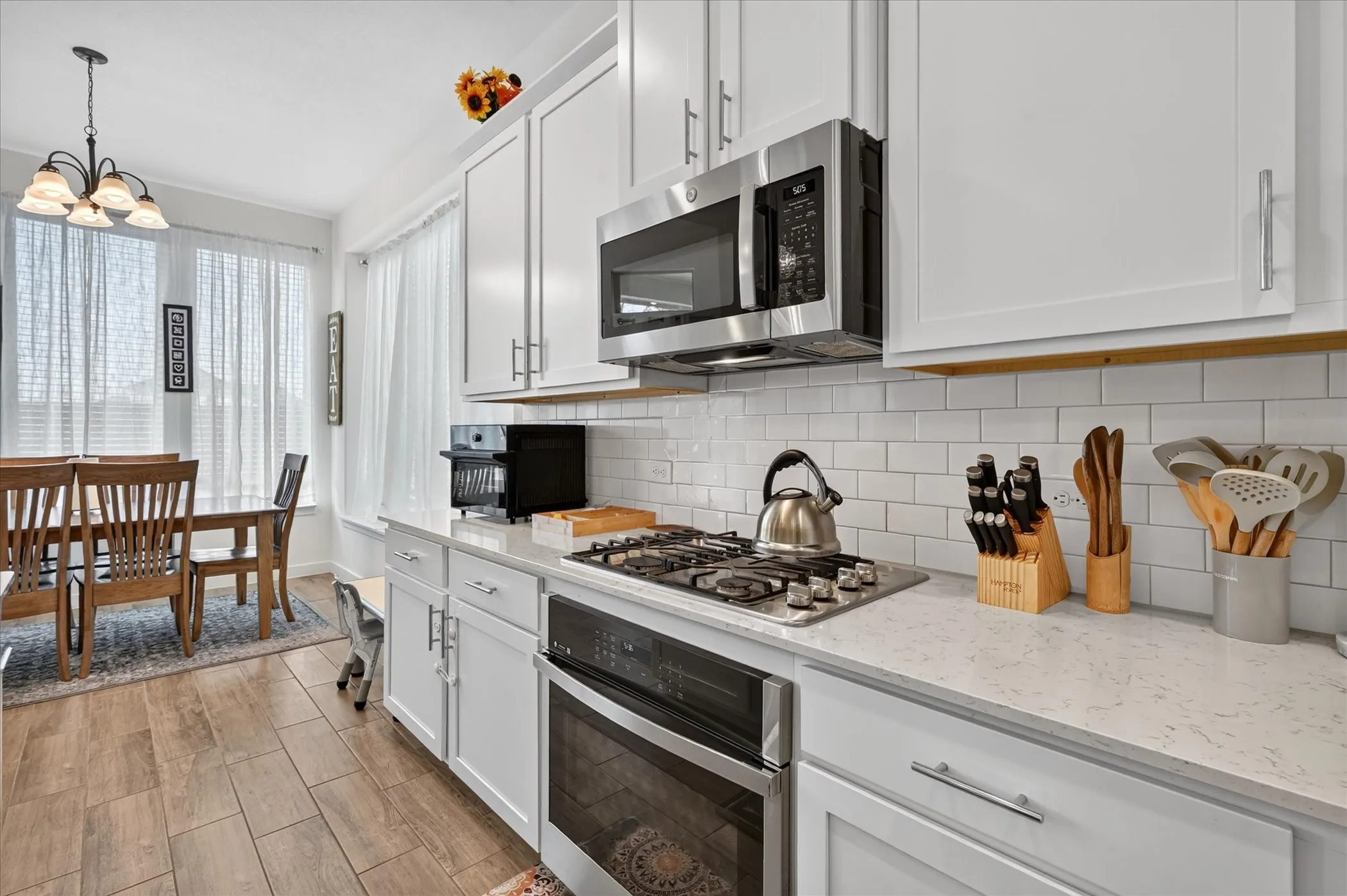 Kitchen featuring white shaker-style cabinetry, stainless steel appliances, a white subway tile backsplash, and light-colored countertops