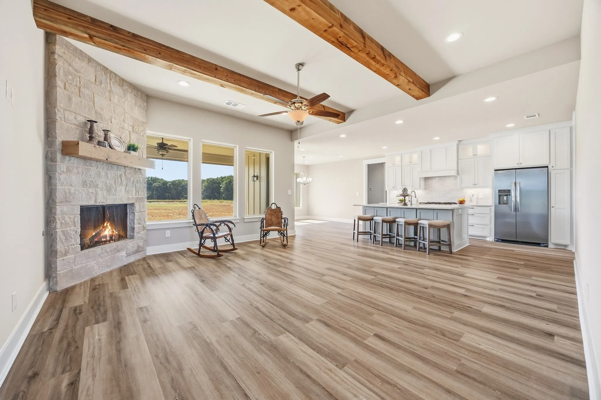 Living room with stone gas fireplace, wood beams and wall of windows