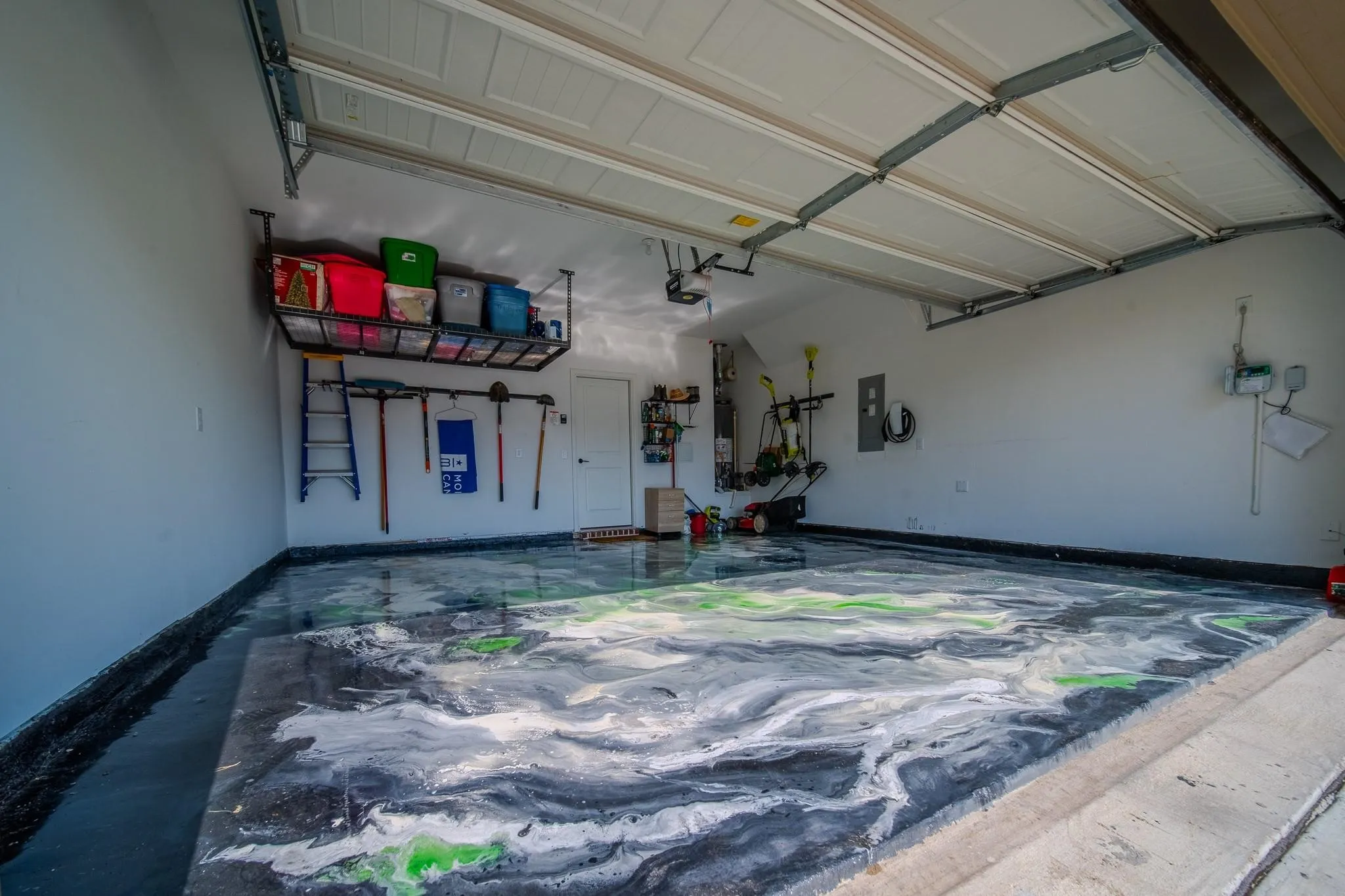 Garage featuring a decorative epoxy floor finish, overhead storage racks, and white interior walls