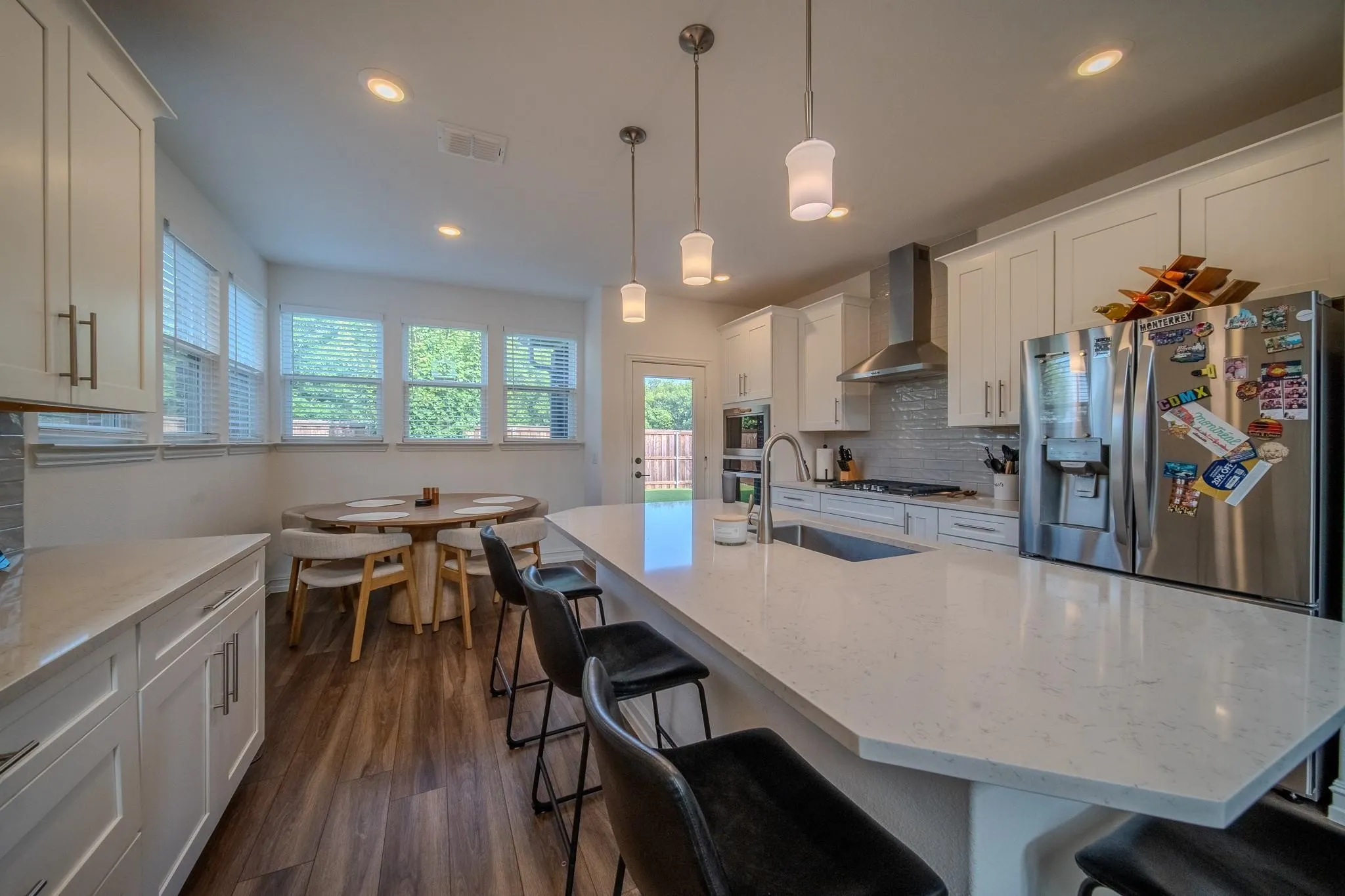 Modern kitchen featuring white cabinetry, a large center island with seating, stainless steel appliances, and wood-finish flooring