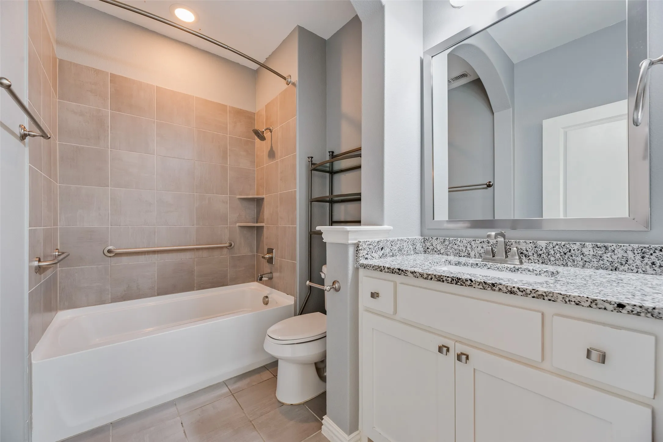 White vanity with a granite countertop, undermount sink, and brushed nickel hardware