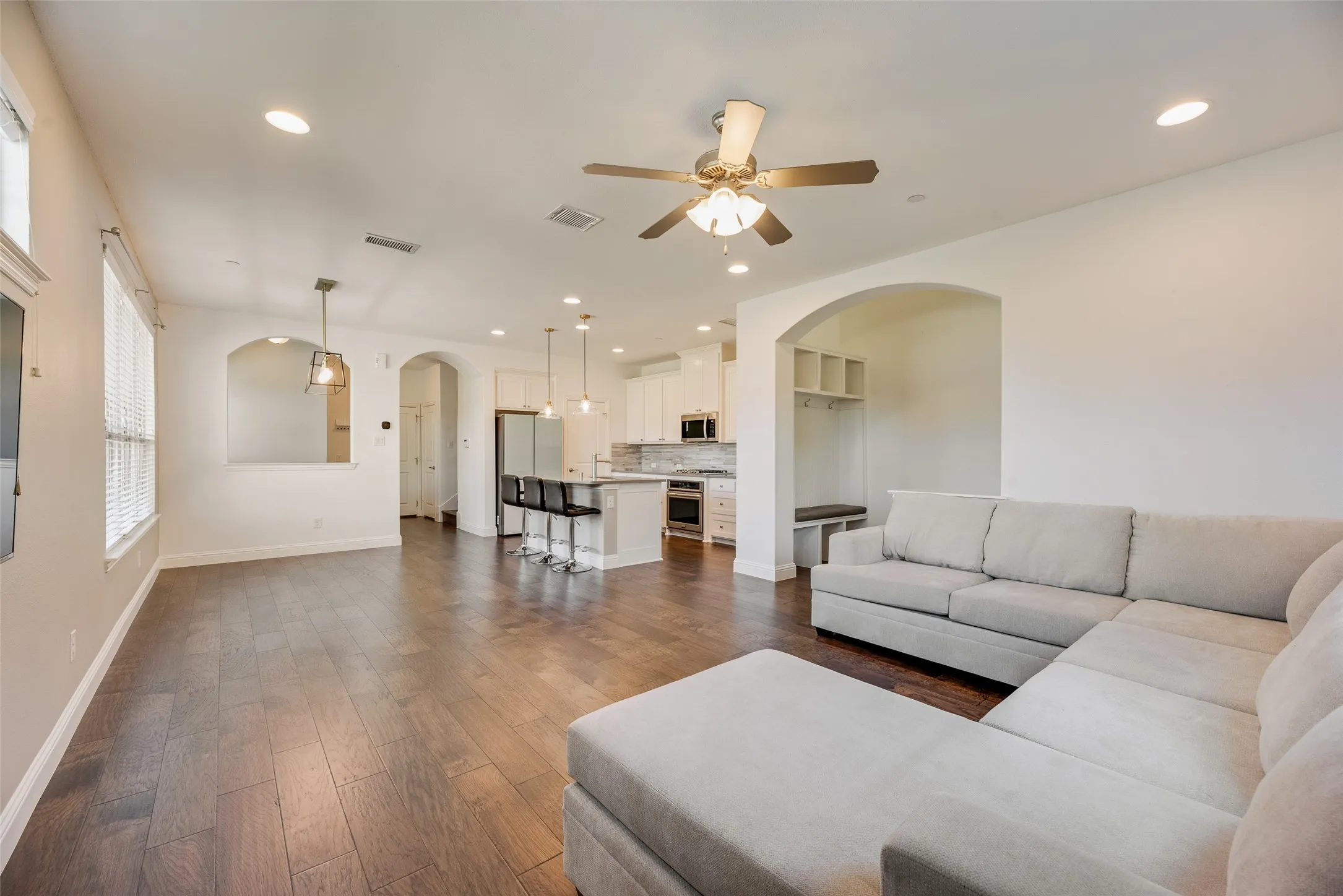 Wood-finish flooring throughout, recessed lighting, ceiling fan, arched doorways, and a built-in mudroom bench with shelving