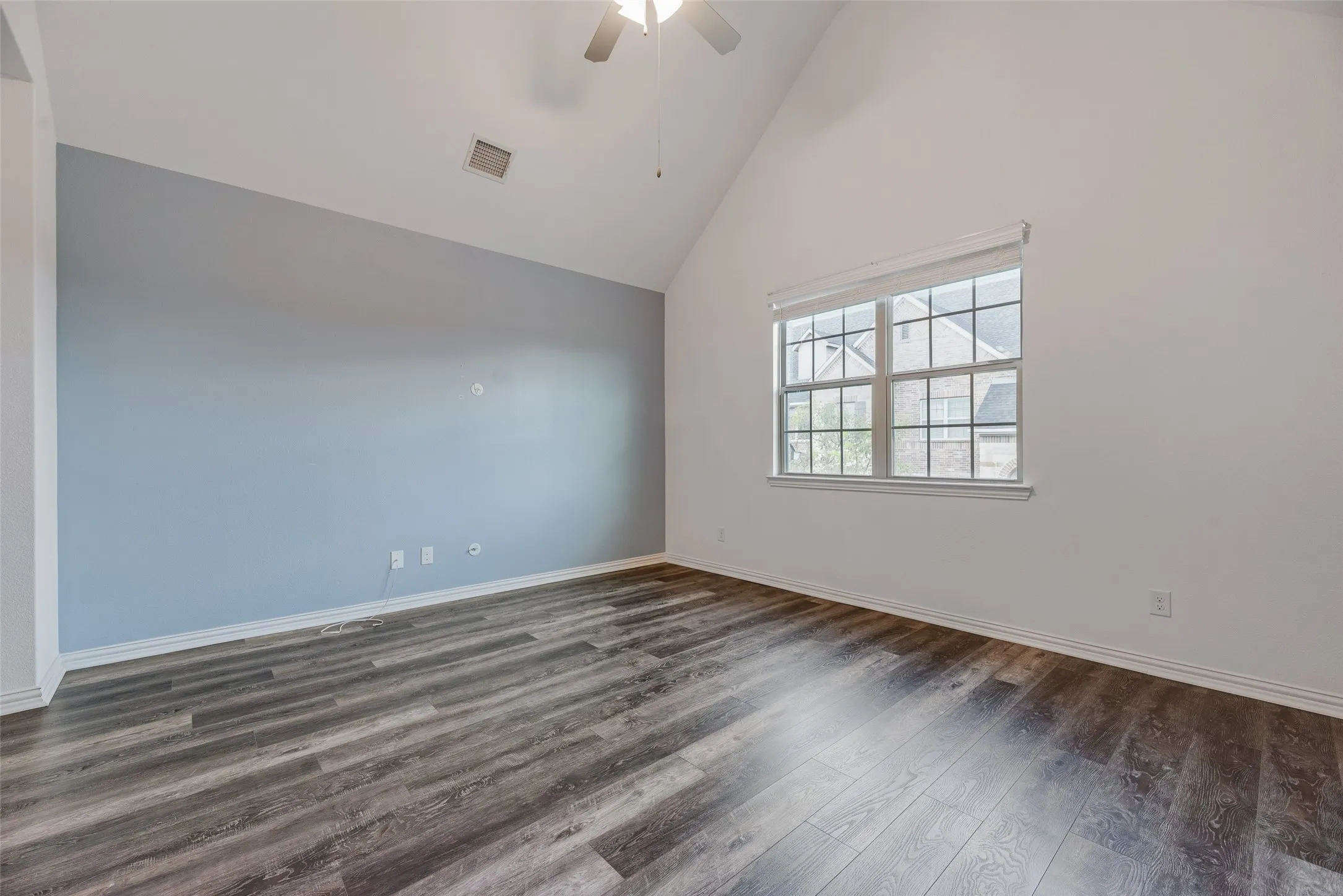 Vaulted ceiling with a ceiling fan, wood-finish flooring, and a large window with blinds
