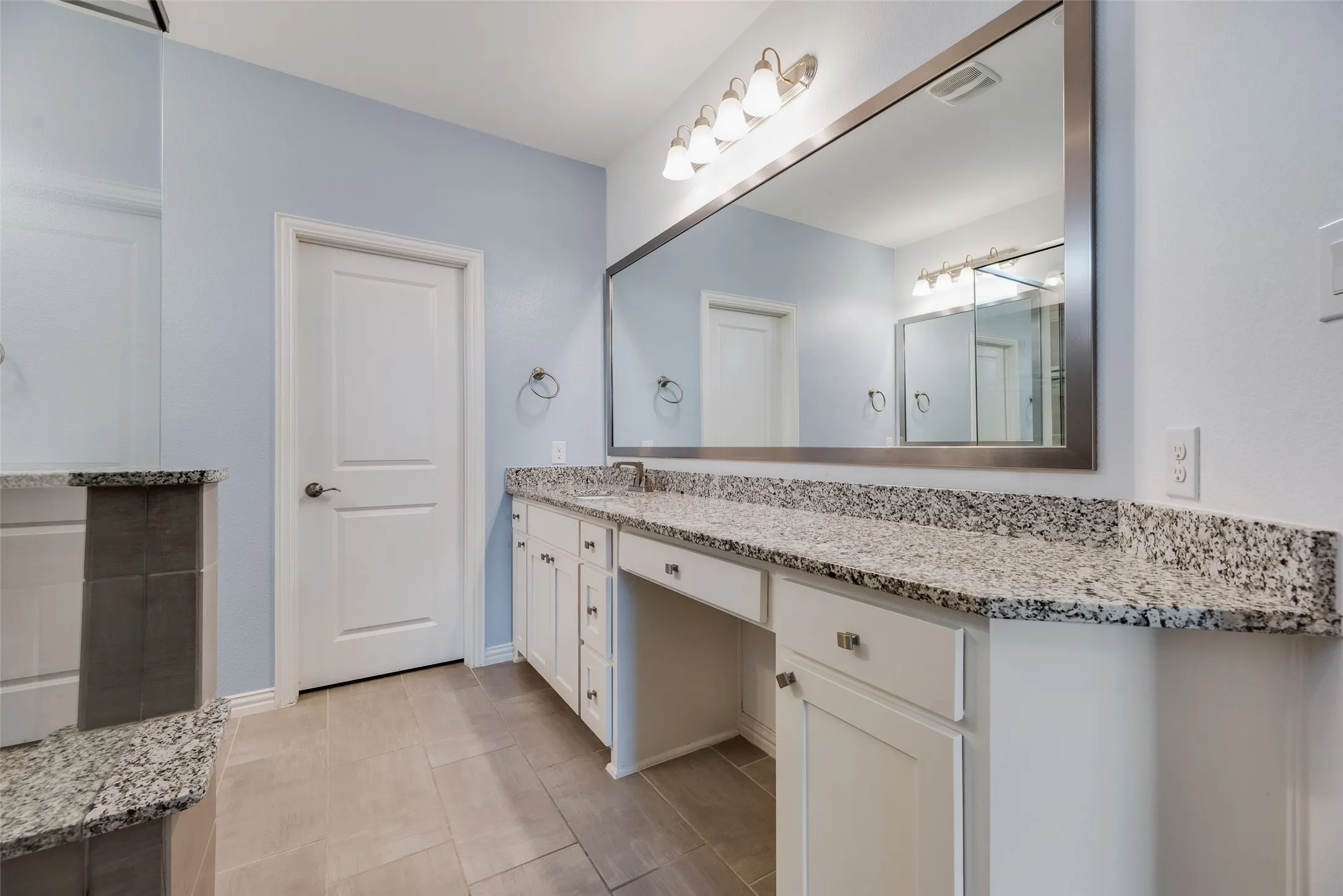 Extended vanity with a granite countertop, undermount sink, and integrated makeup area