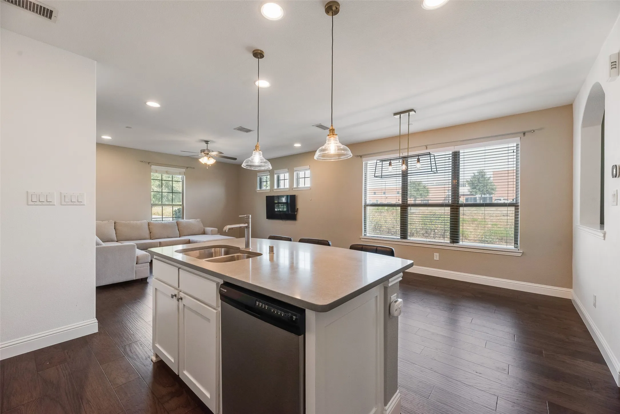 Kitchen island with an undermount double basin sink, stainless steel dishwasher, and a stone countertop