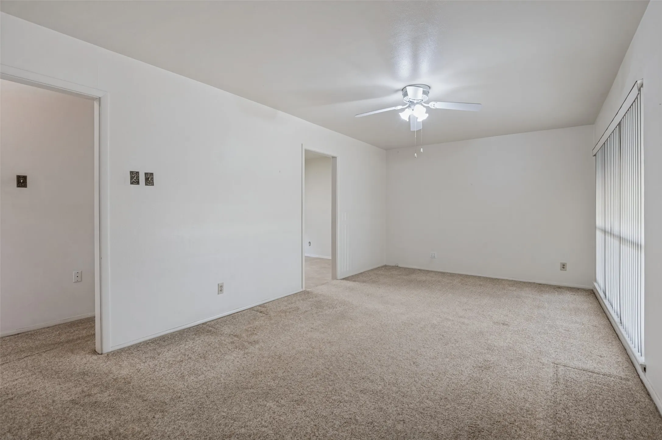 Carpeted interior space with a ceiling fan, recessed lighting, and vertical window blinds