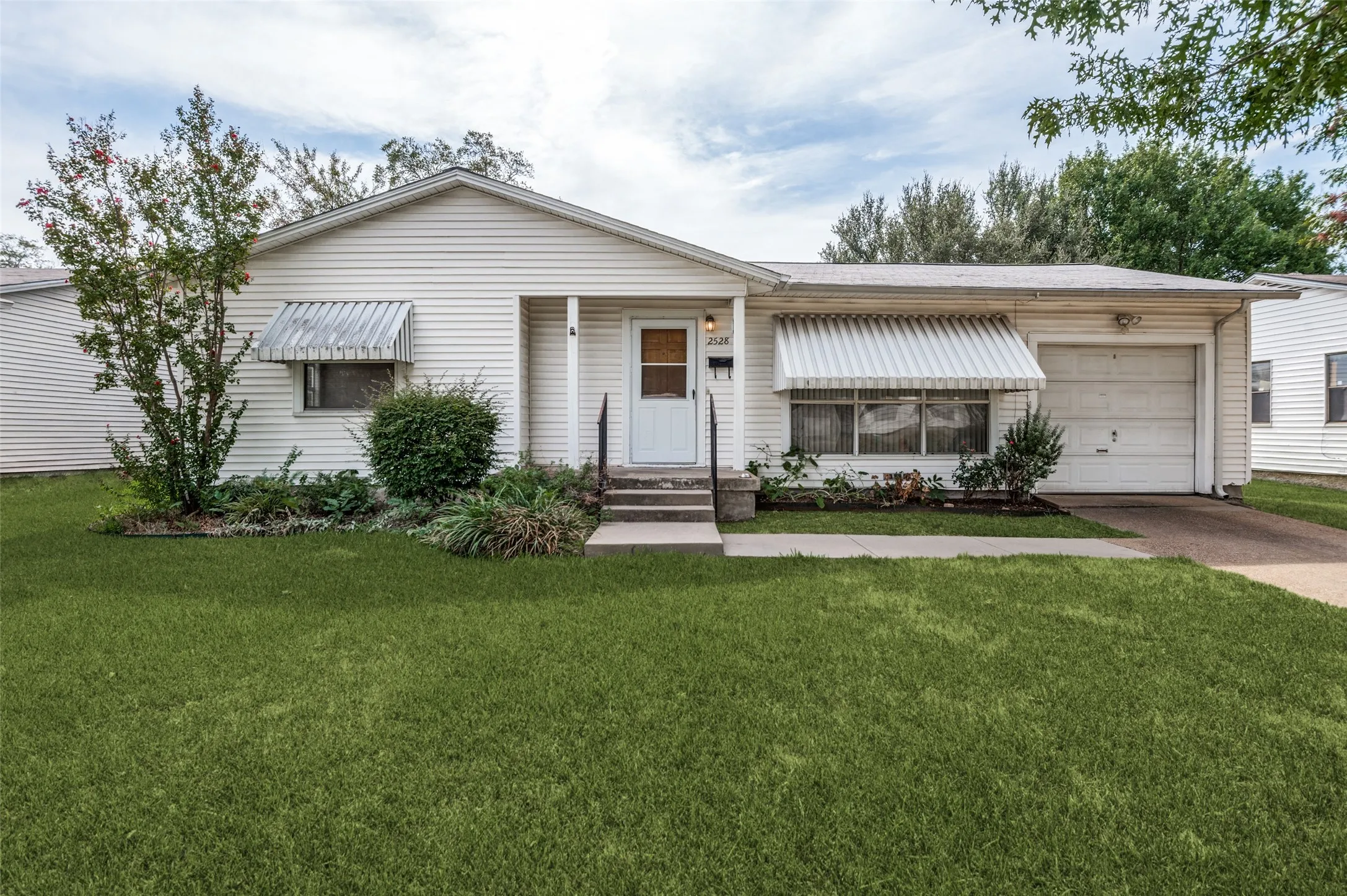 White siding exterior with a single-car garage and concrete driveway