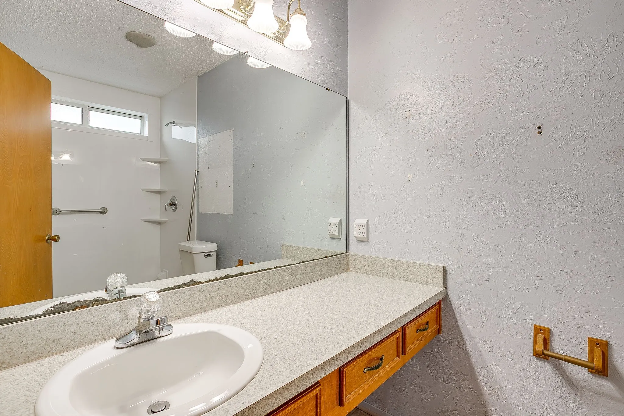 Vanity with an integrated white sink and chrome faucet, set into a stone-look countertop