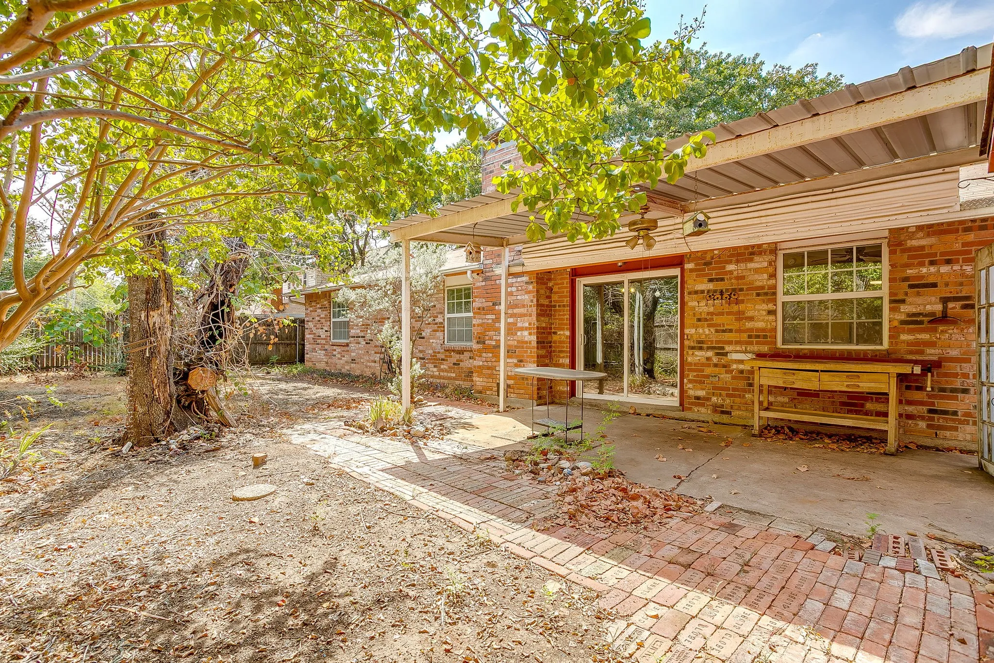 Brick exterior with a covered patio area, large sliding glass door, and a brick paver pathway
