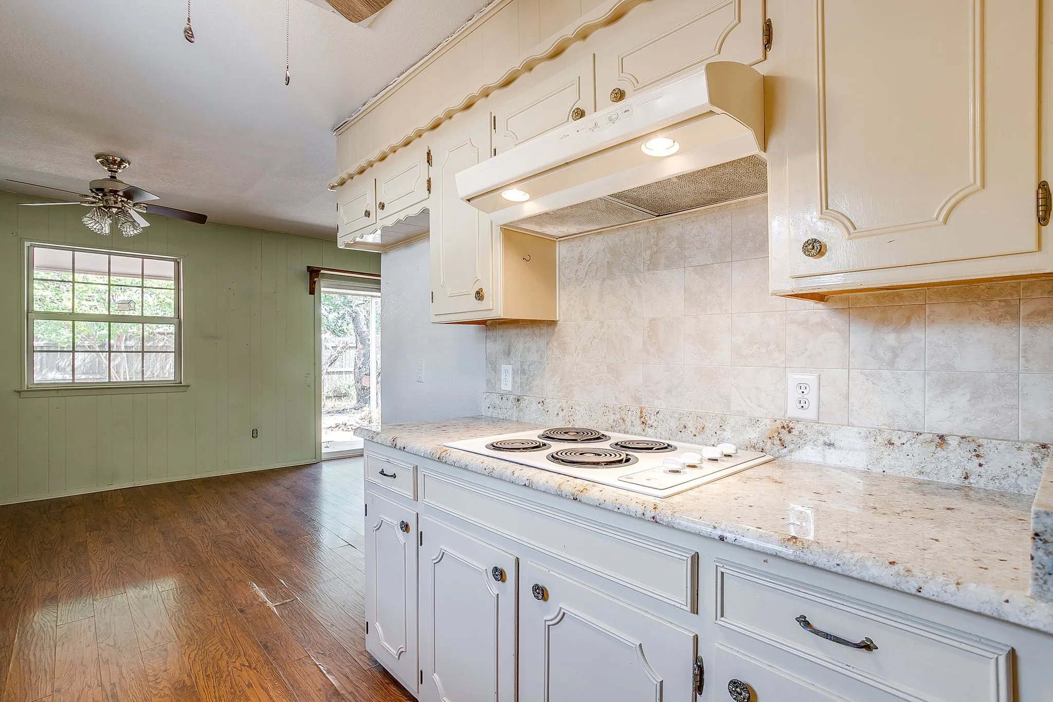 Kitchen featuring light-toned cabinetry, a built-in cooktop, and speckled countertops