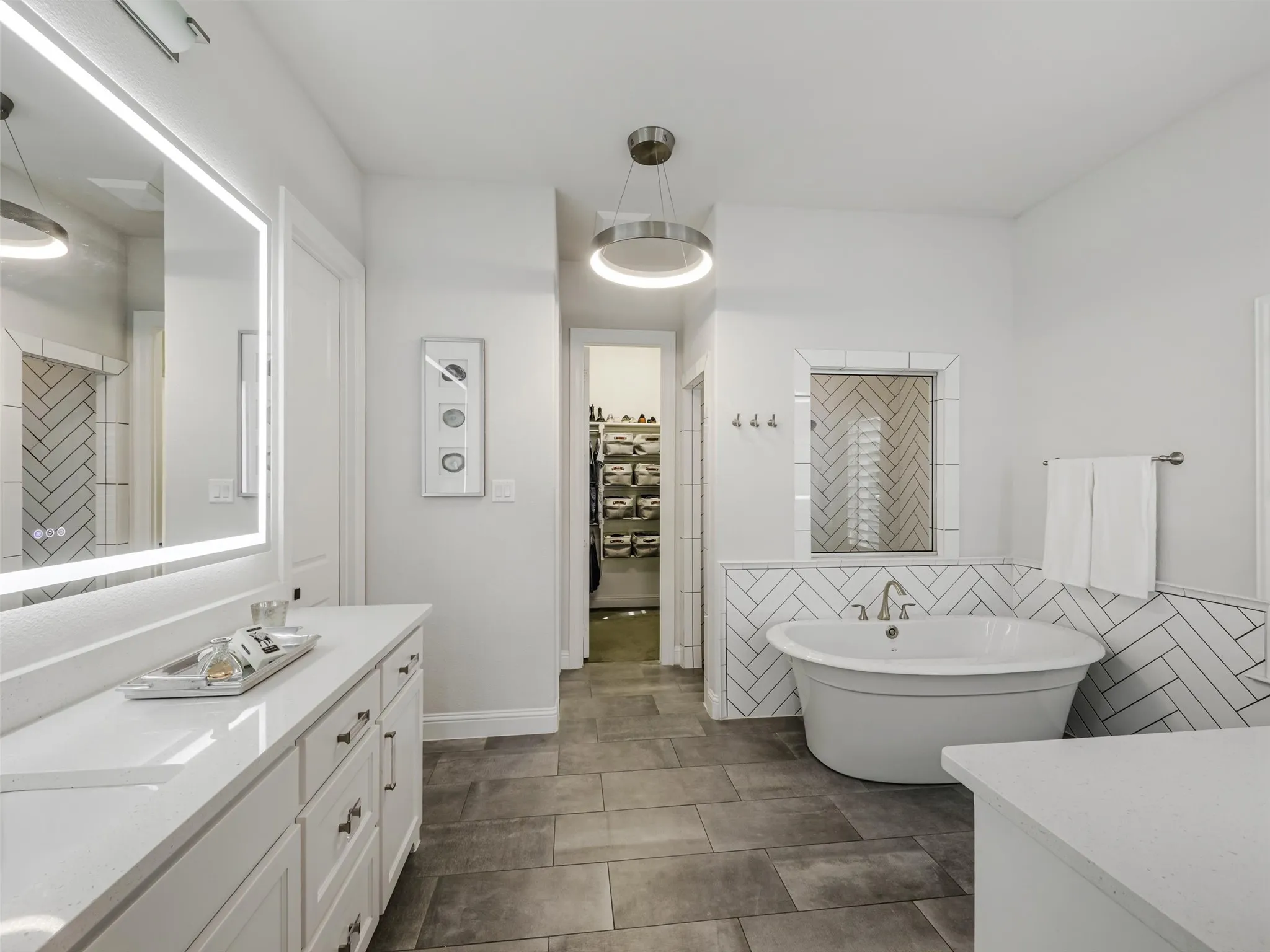 The spa-inspired bathroom features dual vanities with sinks, a soaking tub, an oversized walk-in shower, and separate his-and-hers walk-in closets. • White oak flooring
• Vaulted ceilings
• Custom accent wall