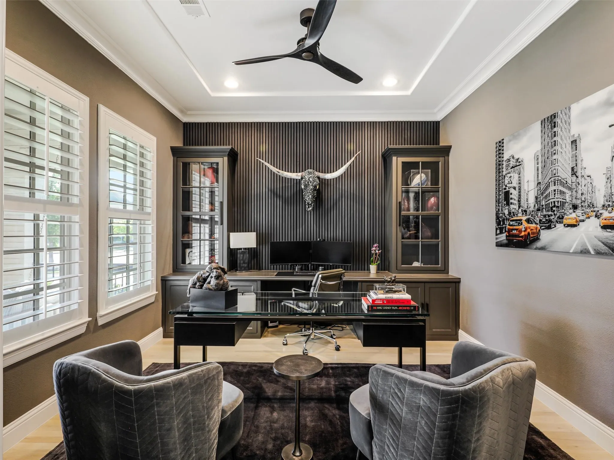 Just off the entry, the private study provides an ideal setting for working from home, featuring French doors, a tray ceiling, plantation shutters, a ceiling fan, and custom built-in desk and shelving. • White oak flooring throughout the first floor
• Foyer: Restoration Hardware chandelier
• Dining room: custom carpentry and Williams Sonoma chandelier
• Office: custom built-ins
• Game room: custom carpentry and dry bar
• Media room: Epson 4K projector