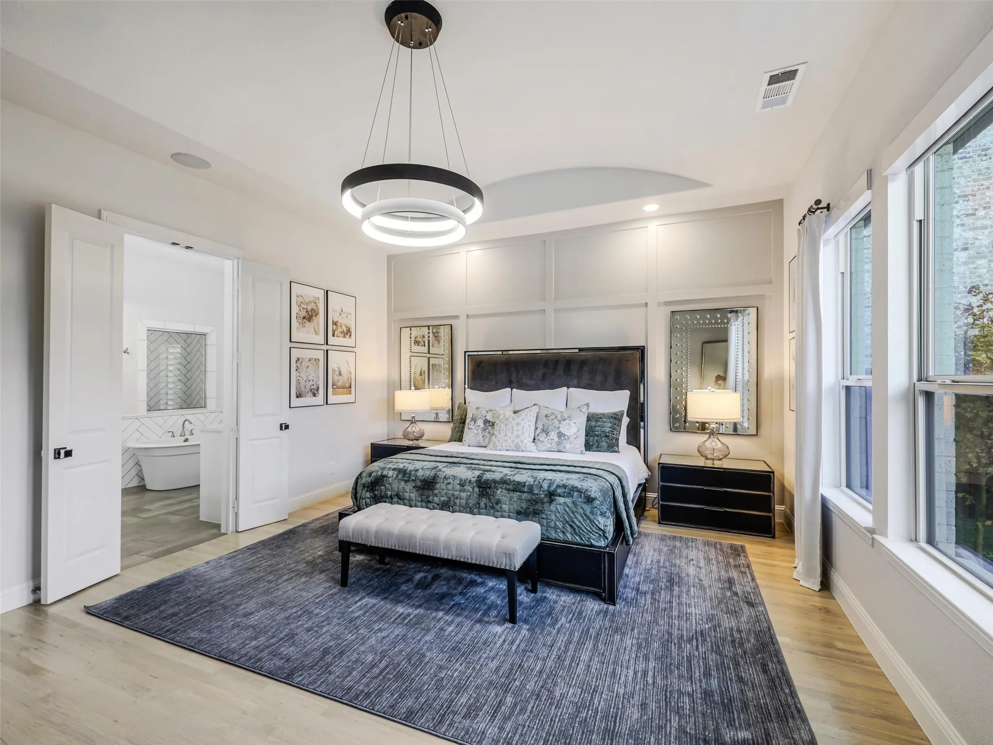 The downstairs primary retreat offers a private escape with a vaulted ceiling, chandelier, electric, remote-controlled shades, and a spacious ensuite bath