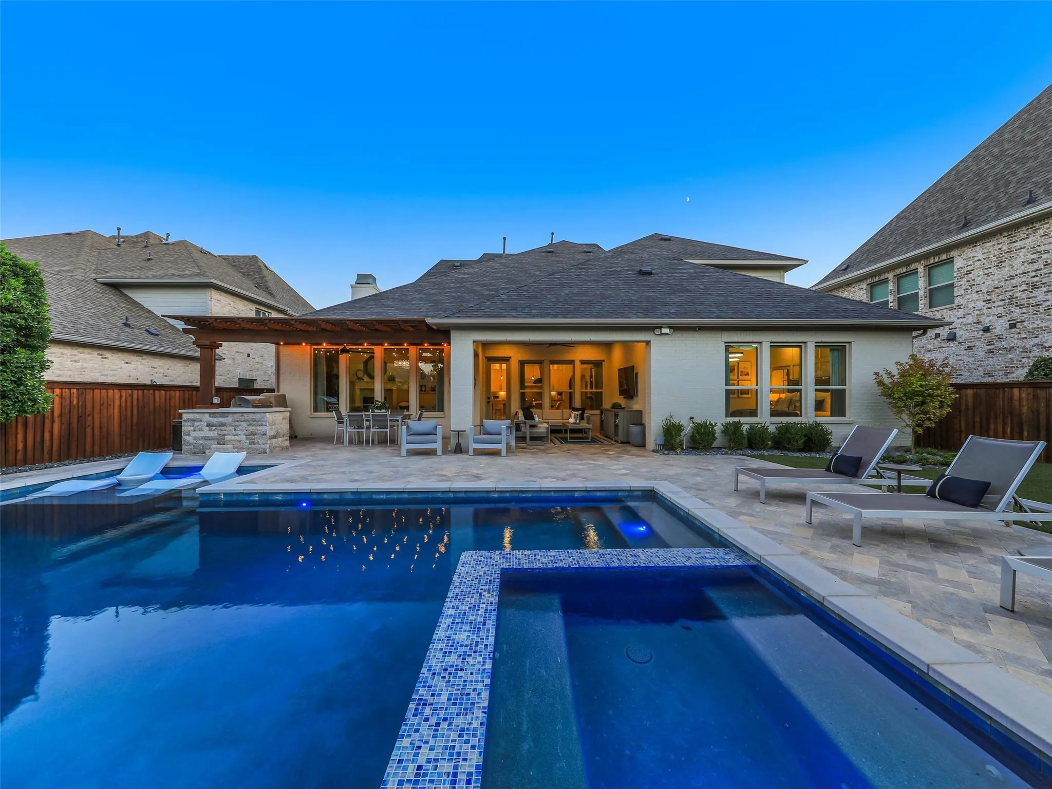 The resort-style heated pool and spa are designed for year-round enjoyment and feature a Baja shelf with Ledge Lounger Signature chaises and a table, along with a built-in basketball goal for added fun. • Custom pool and spa ranging from 3.5 ft in the shallow end to 6 ft in the deep end, with basketball hoop
• Baja shelf with lounge chaises and table
• 5 Jandy pool lights, recently replaced
• Silver travertine decking throughout pool and patio
• Pergola over outdoor living area
• Built-in outdoor kitchen with Bull grill and Bull refrigerator
• Fire pit patio
• Artificial turf, approx. 21 ft x 38 ft
• Mature landscaping with landscape lighting
• Decorative rock: approx. 15 tons of large Texas black rock and 3 tons of black Mexican river stone
• Built-in speakers in the patio ceiling and throughout the pool and landscape areas