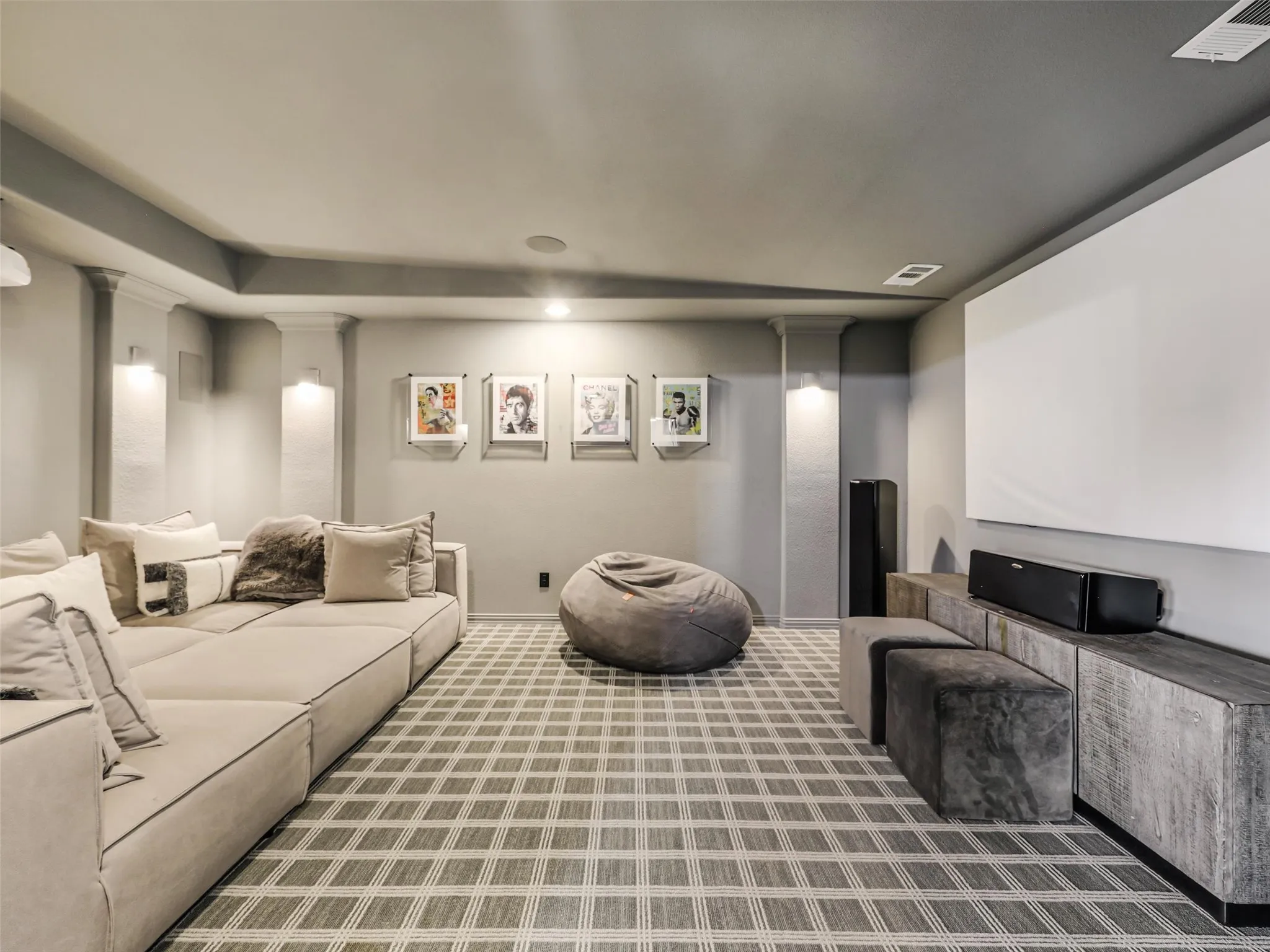 A dedicated media room with wall sconces and recessed lighting provides the perfect setting for movie night. • White oak flooring throughout the first floor
• Foyer: Restoration Hardware chandelier
• Dining room: custom carpentry and Williams Sonoma chandelier
• Office: custom built-ins
• Game room: custom carpentry and dry bar
• Media room: Epson 4K projector