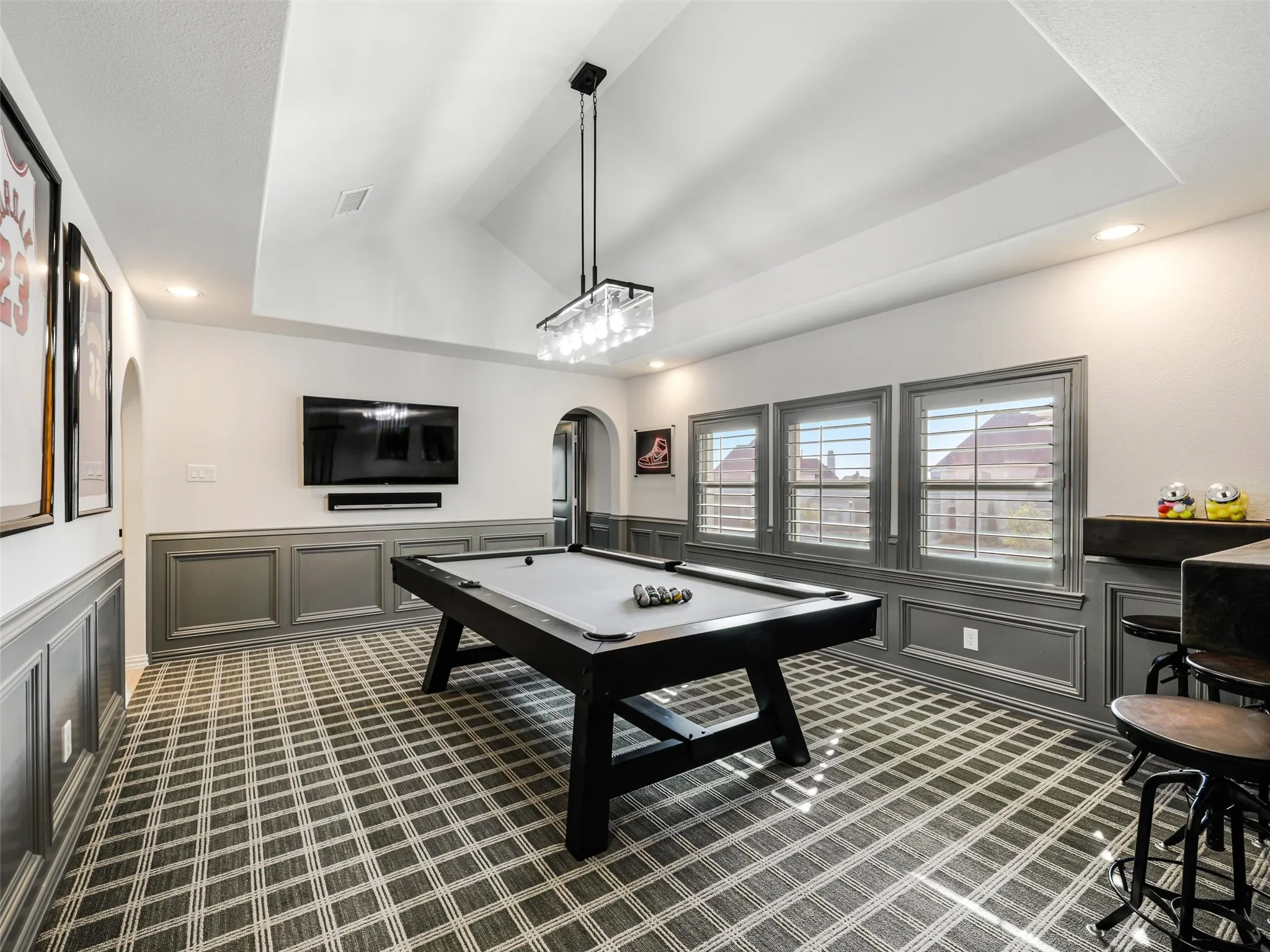 Upstairs, the home continues to impress with an expansive game room featuring a vaulted ceiling, dry bar, and plantation shutters. • White oak flooring throughout the first floor
• Foyer: Restoration Hardware chandelier
• Dining room: custom carpentry and Williams Sonoma chandelier
• Office: custom built-ins
• Game room: custom carpentry and dry bar
• Media room: Epson 4K projector