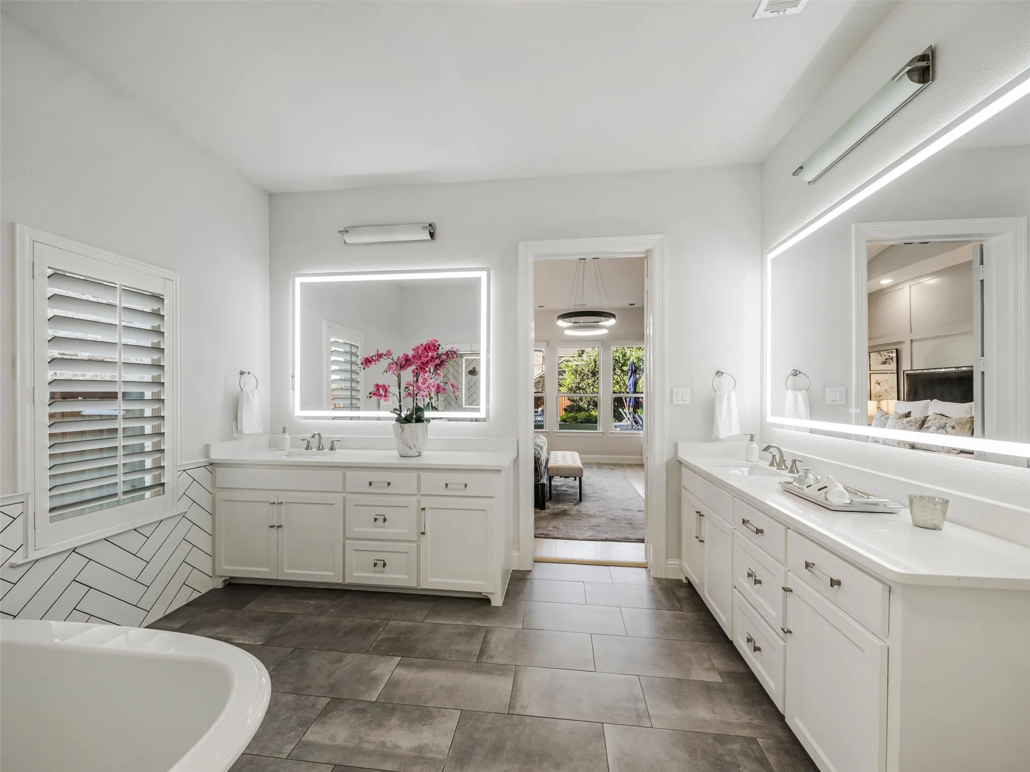 The spa-inspired bathroom features dual vanities with sinks, a soaking tub, an oversized walk-in shower, and separate his-and-hers walk-in closets. • White oak flooring
• Vaulted ceilings
• Custom accent wall