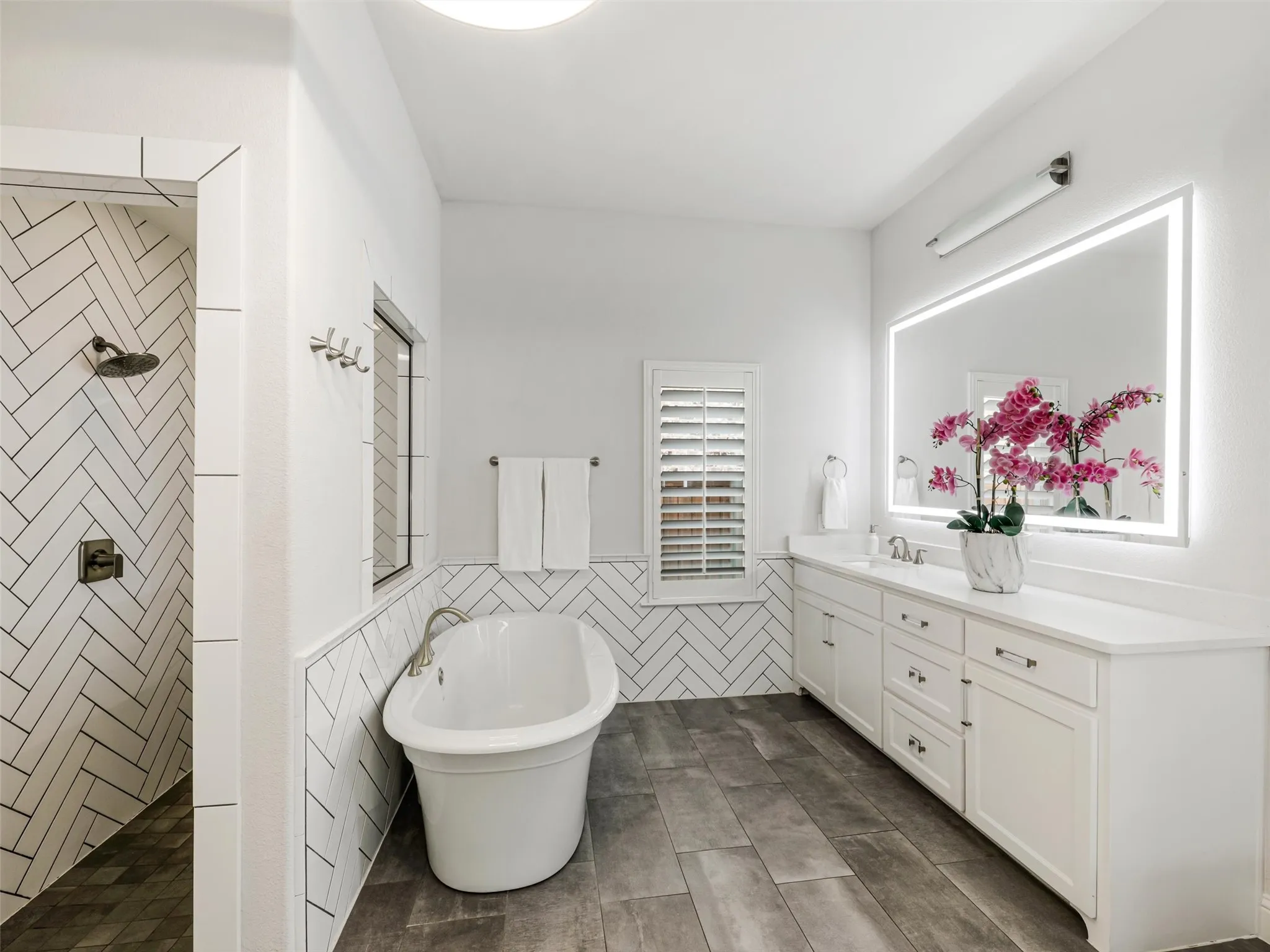 The spa-inspired bathroom features dual vanities with sinks, a soaking tub, an oversized walk-in shower, and separate his-and-hers walk-in closets. • White oak flooring
• Vaulted ceilings
• Custom accent wall