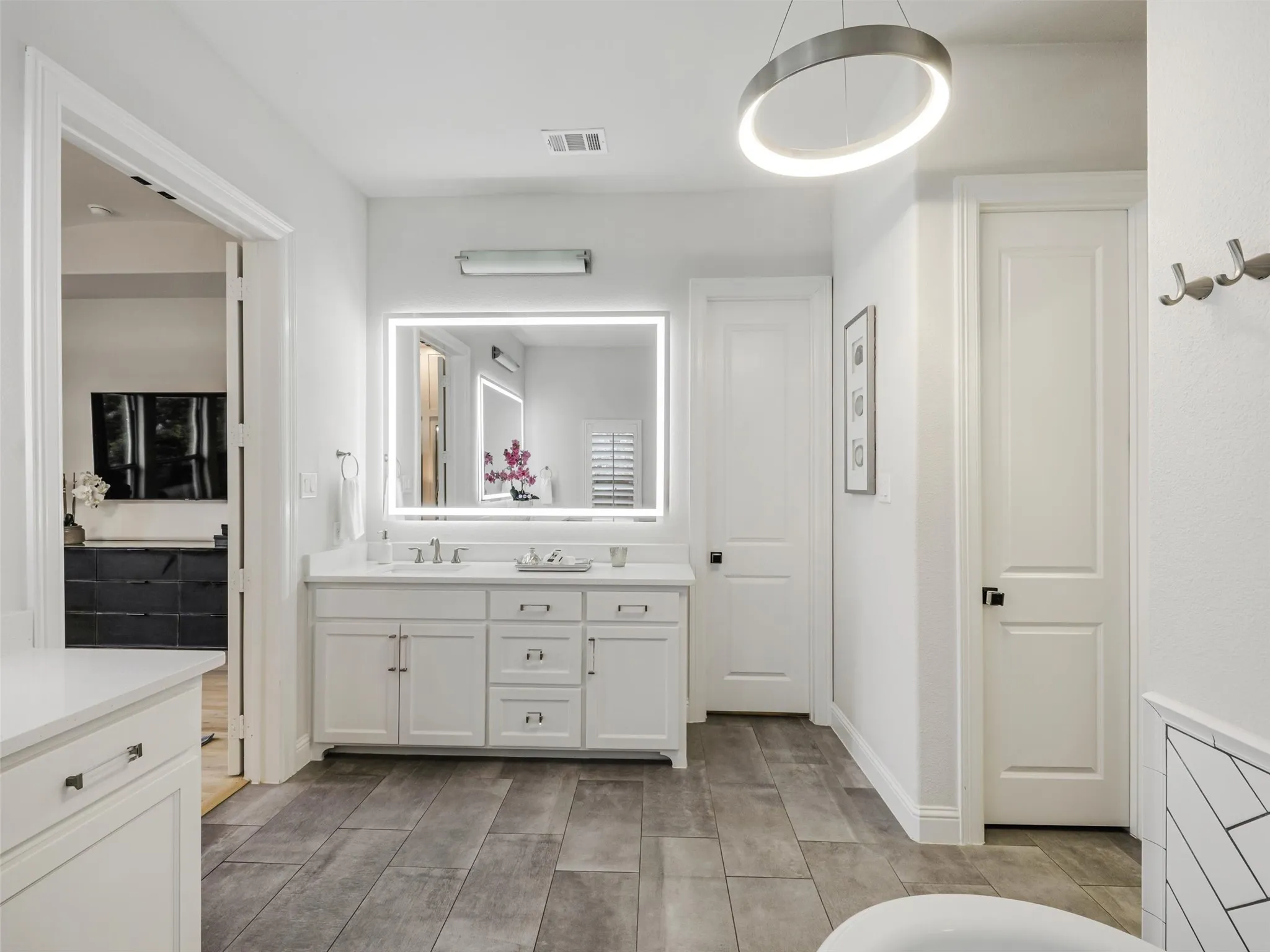 The spa-inspired bathroom features dual vanities with sinks, a soaking tub, an oversized walk-in shower, and separate his-and-hers walk-in closets. Thoughtful planning continues with direct access from the primary suite to the laundry room, making everyday routines exceptionally convenient. The oversized laundry room offers abundant storage along with dedicated space for an additional refrigerator or freezer. • White oak flooring
• Vaulted ceilings
• Custom accent wall