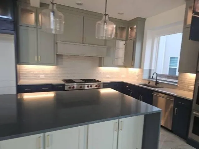 Spacious kitchen featuring an island with a dark countertop, two-tone cabinetry, stainless steel appliances, and a tiled backsplash
