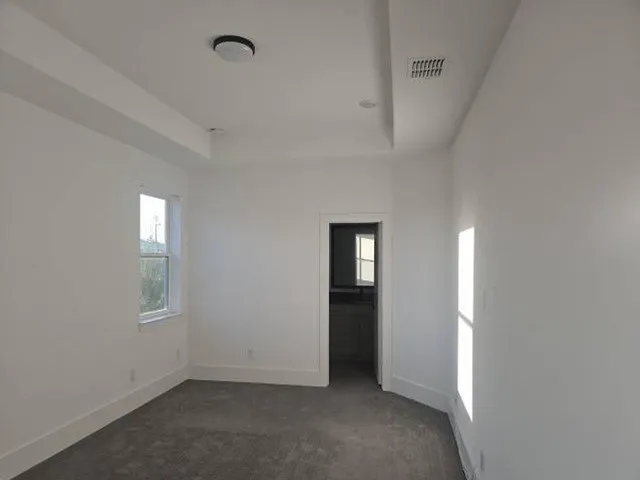 Recessed ceiling detail with flush-mount lighting, neutral carpet flooring, and a single window with white trim