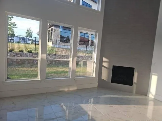 Two-story living area featuring a built-in fireplace, large format polished tile flooring, and multiple windows