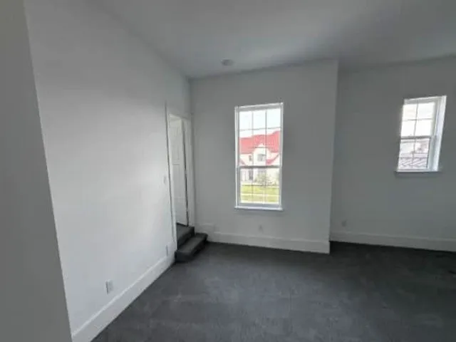 Plush gray carpeting, bright white walls, and two multi-pane windows