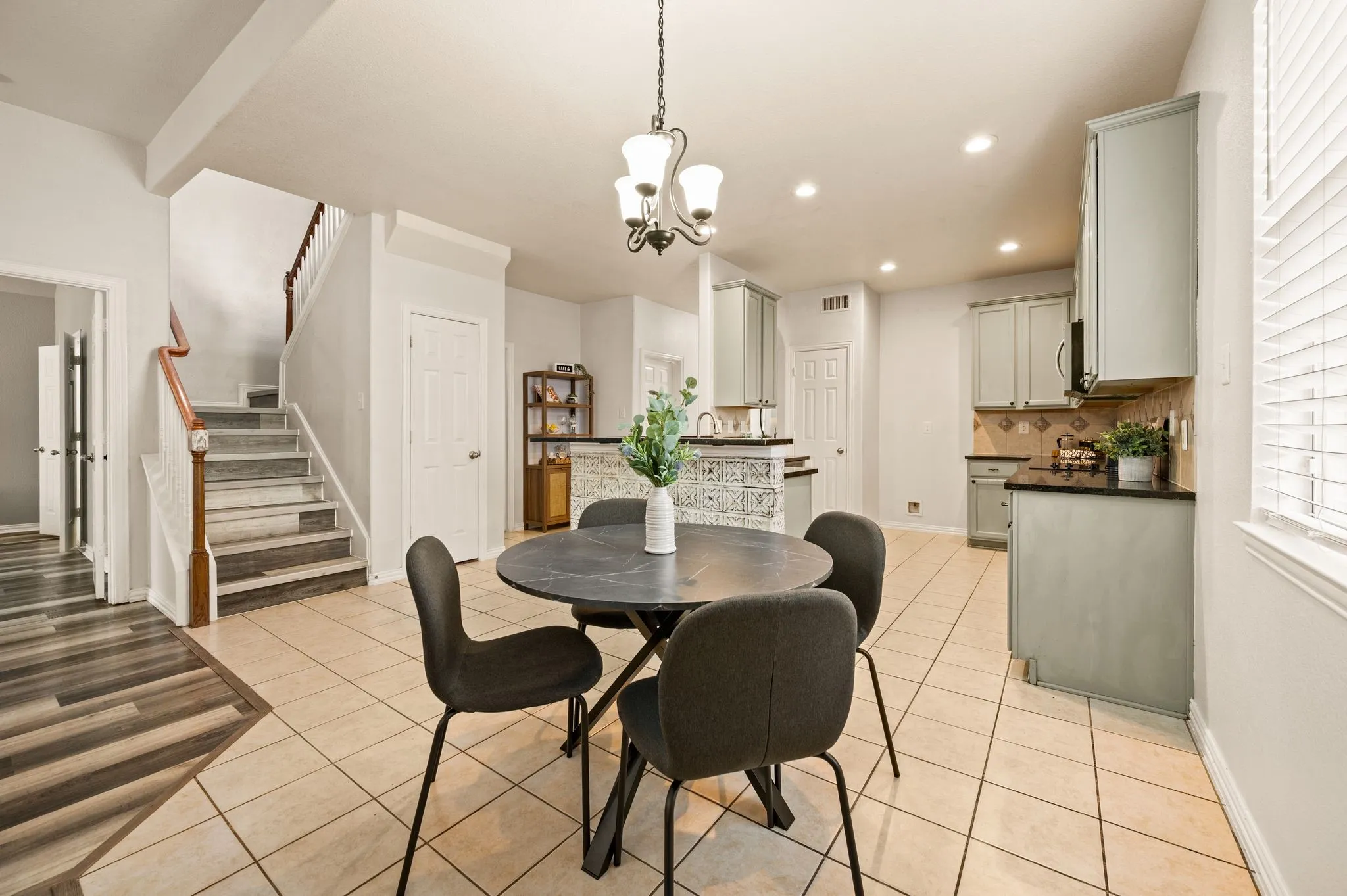 Open-concept kitchen and dining area featuring recessed lighting, a decorative chandelier, and light-toned tile flooring