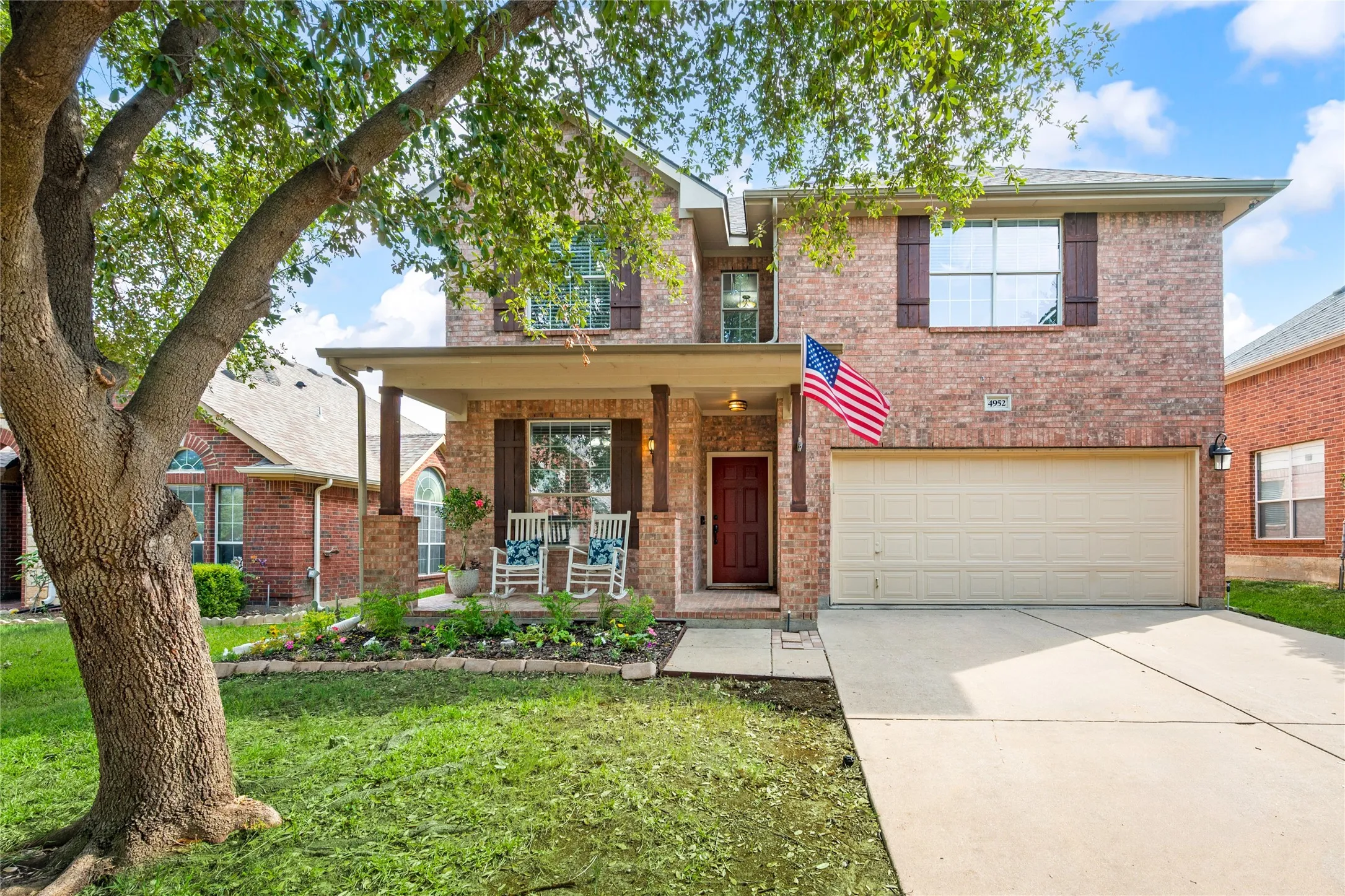 Brick facade residence featuring a covered front porch with substantial columns, a dedicated two-car garage, and a concrete driveway