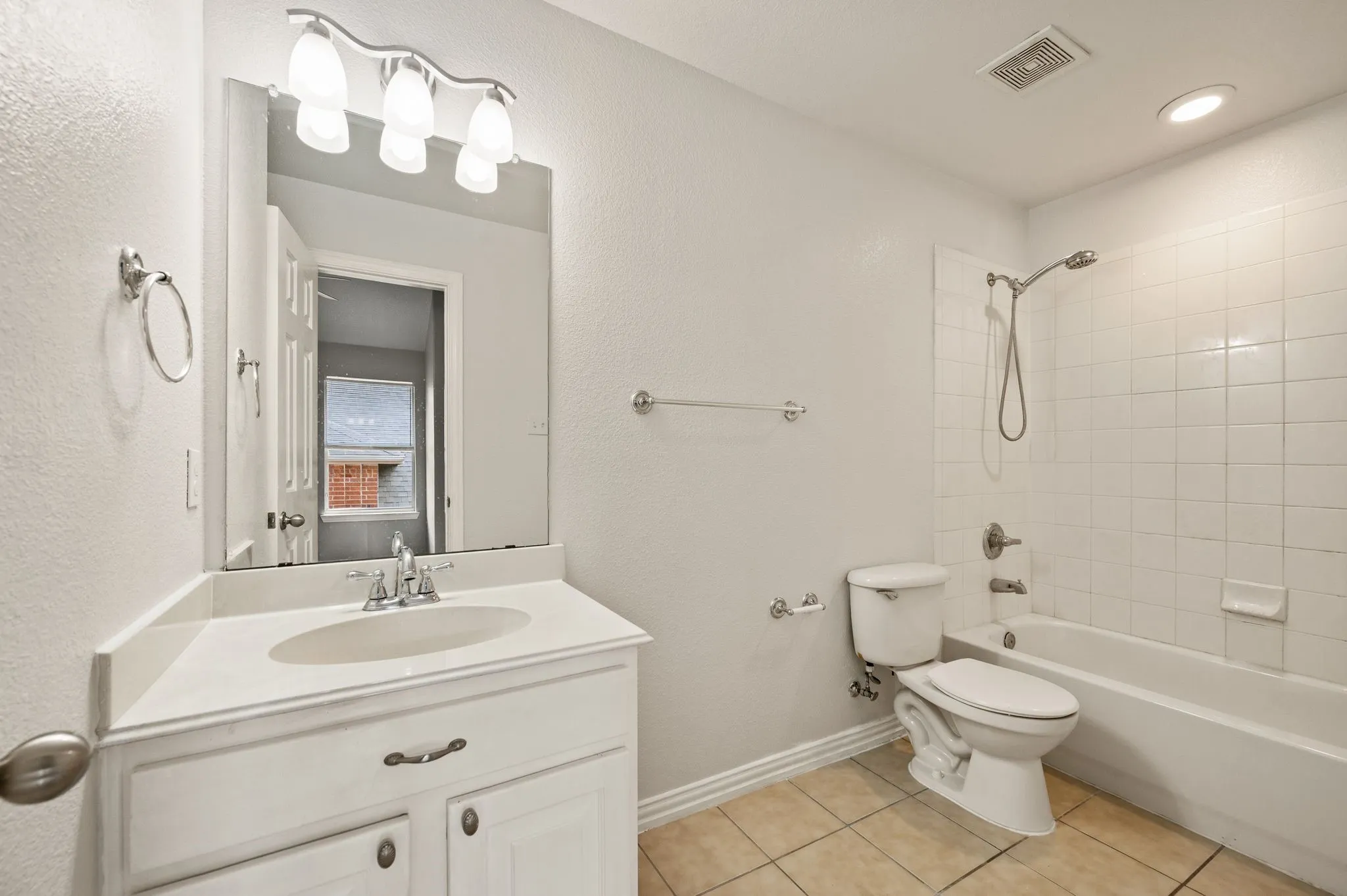 Bathroom with a white vanity featuring an integrated sink, brushed nickel fixtures, a full-width mirror, and a full-size bathtub with a shower