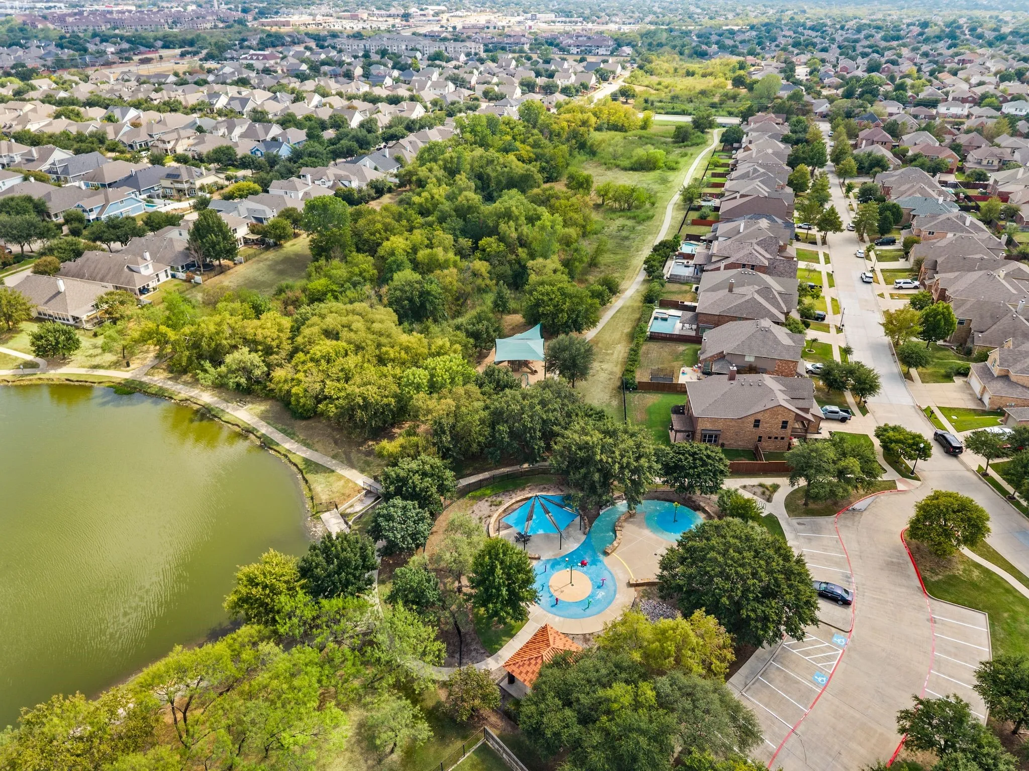 Community lake with a walking paths, and a dedicated recreational area featuring a splash pad