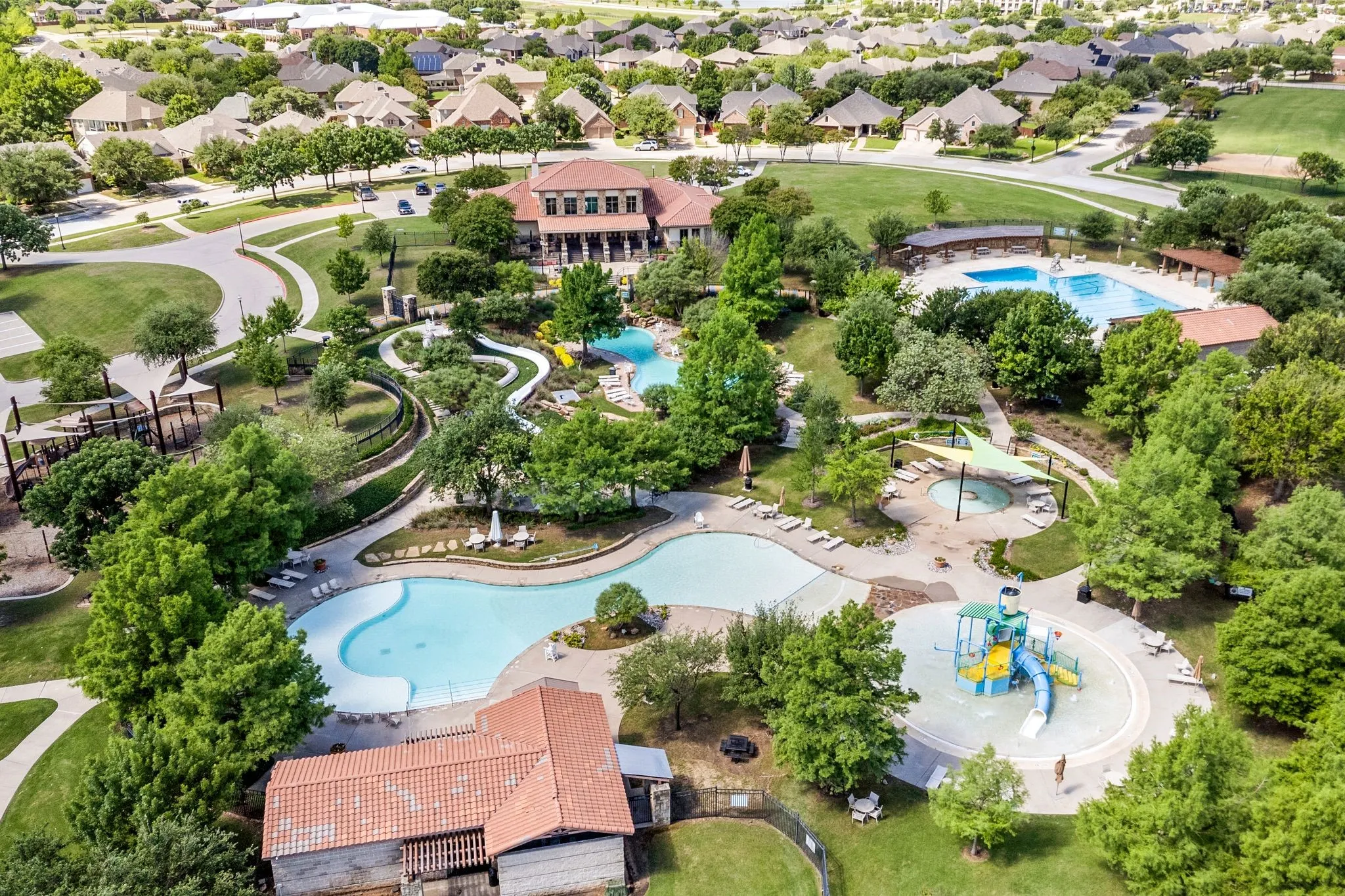 Community amenity center featuring multiple swimming pools, water slides, and a recreational splash pad