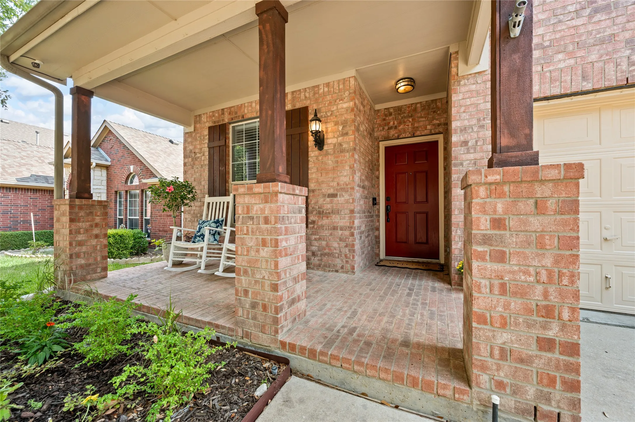 Brick exterior with a covered porch, wood-finish columns, and a red entry door