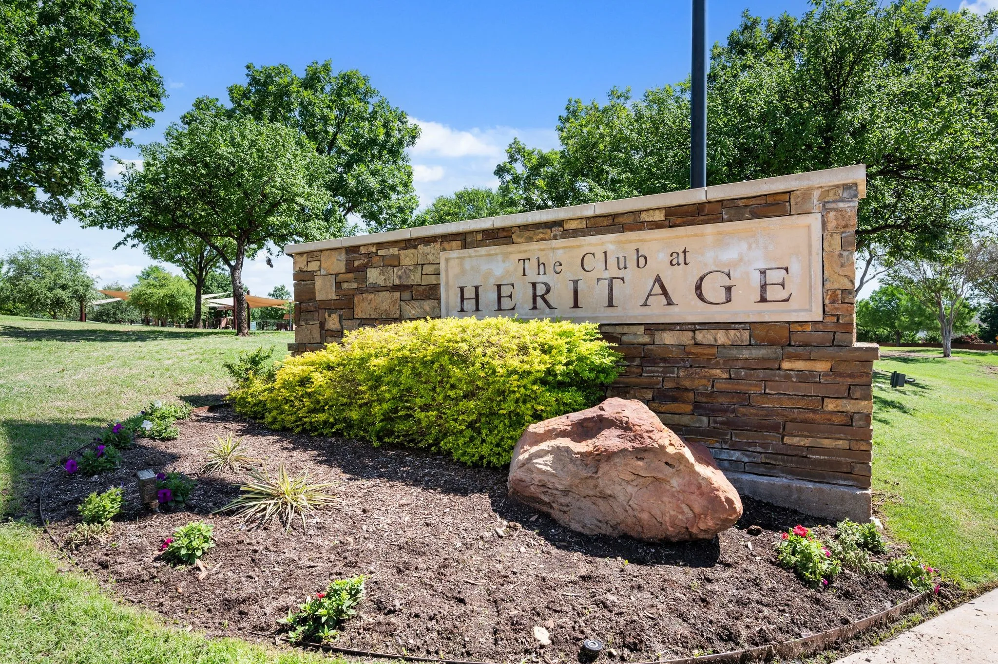 Stone-clad sign with a prominent display of "The Club at Heritage" text