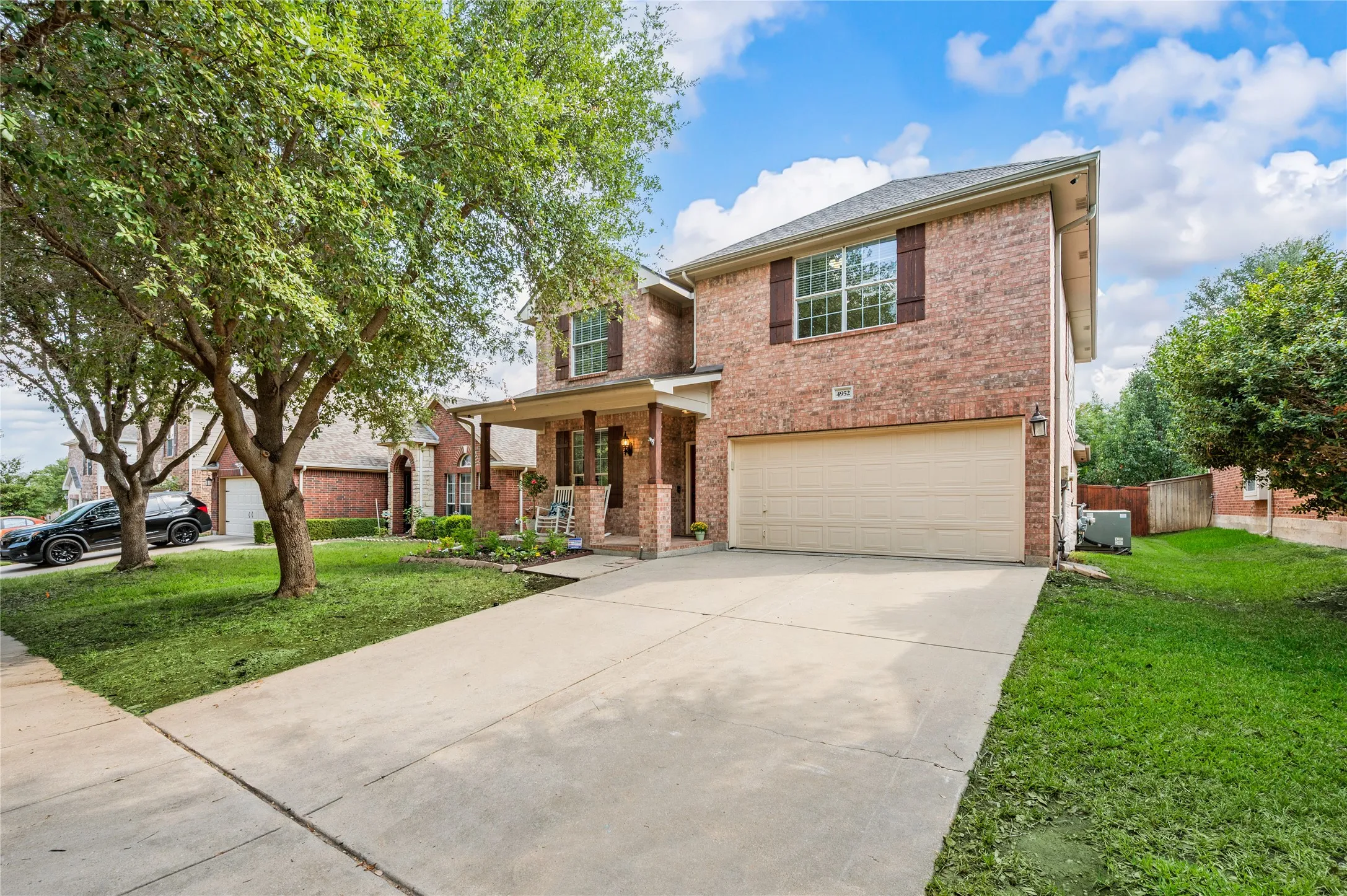 Brick exterior with a covered front porch featuring columns, an attached garage, and a concrete driveway