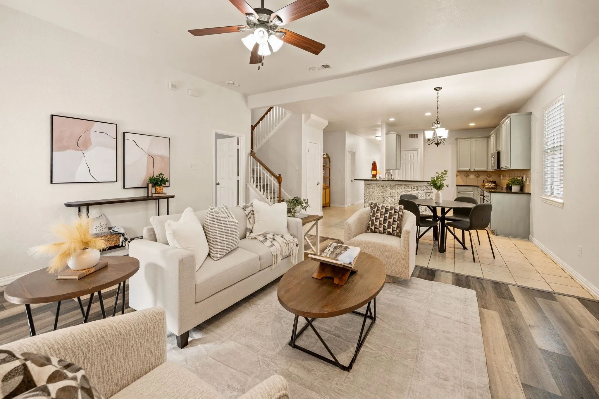 Open-concept living space featuring wood-finish flooring, a ceiling fan, and staircase access