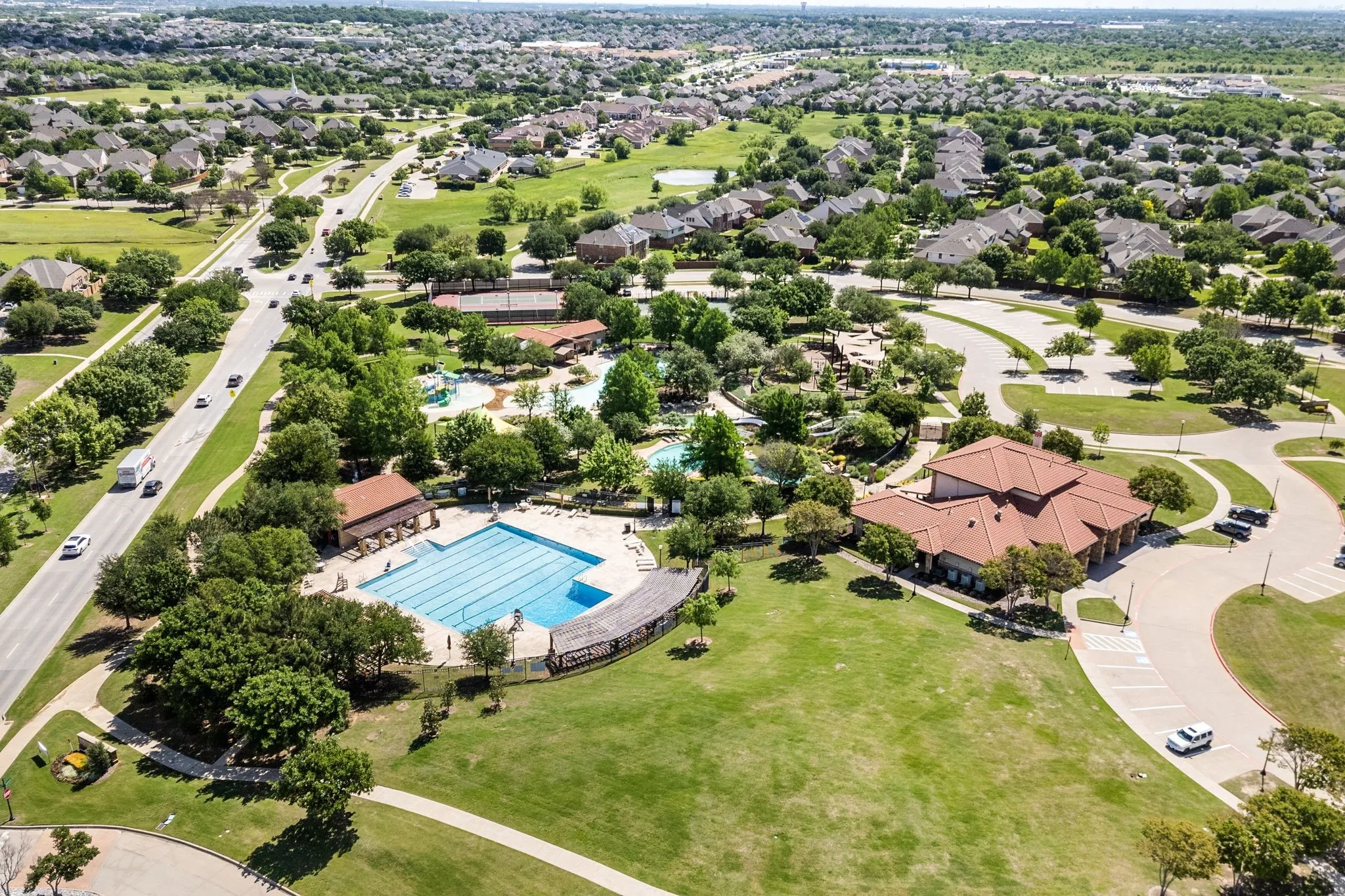 Expansive community grounds featuring a large swimming pool, recreational water features, a dedicated clubhouse, and extensive green spaces