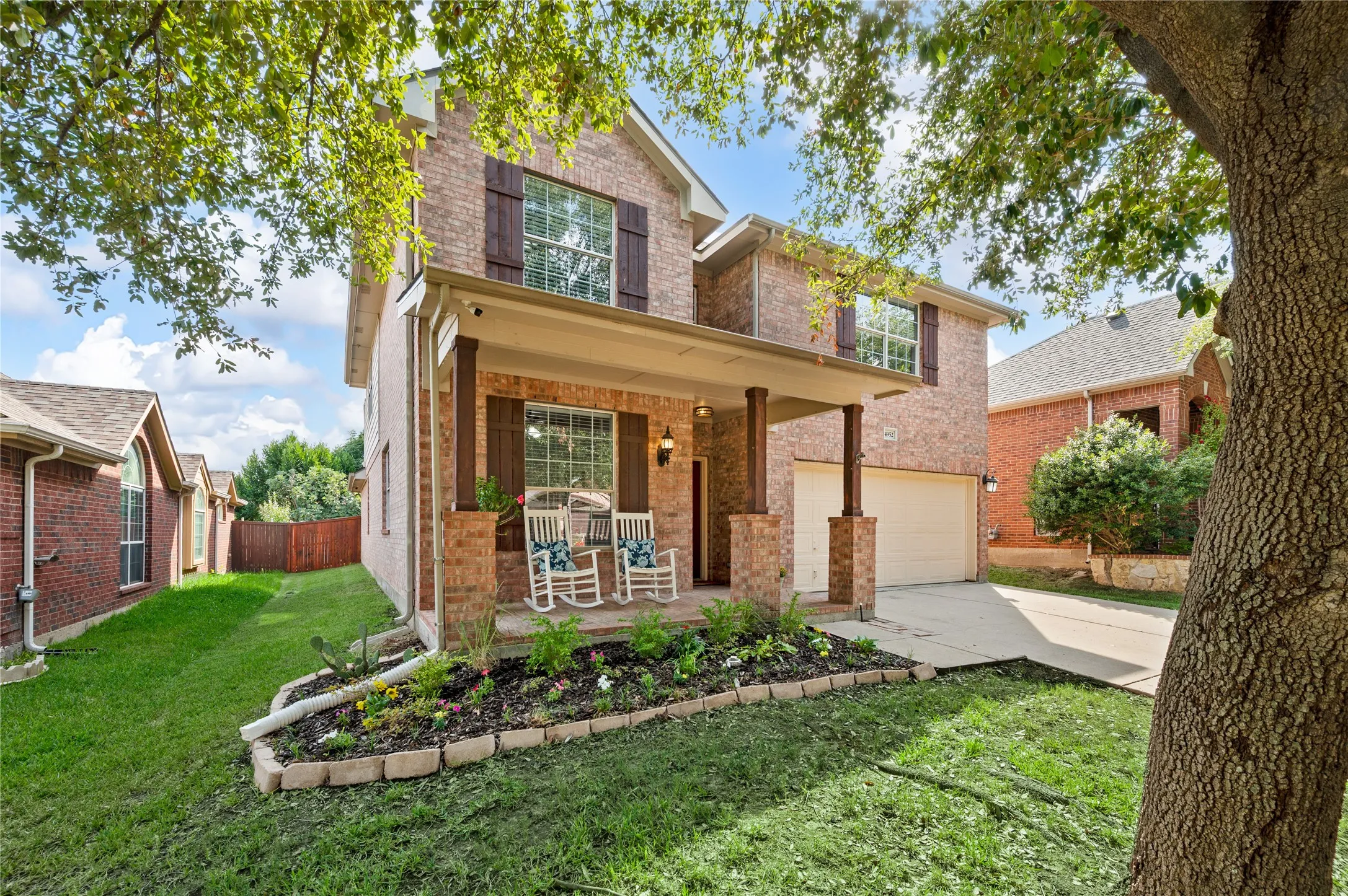 Two-story brick exterior with a covered porch, wood-finish columns, and a two-car garage